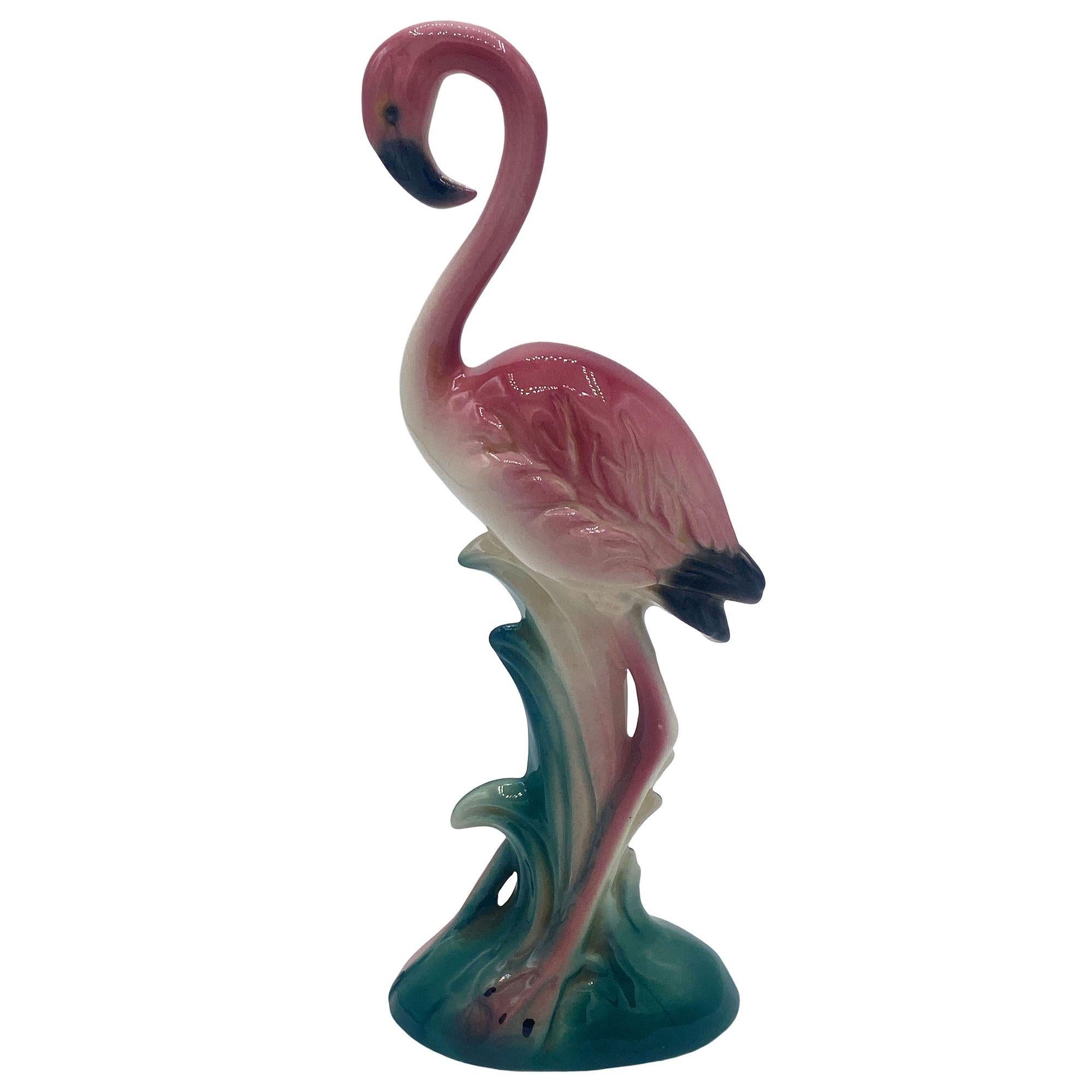Statuetta in ceramica di metà secolo di colore rosa e verde Inquisitive flamingo. La statua raffigurava un fenicottero rosa dalle lunghe zampe, una forma snella e alta che si ergeva su un campo erboso, con un'espressione curiosa. La finitura lucida