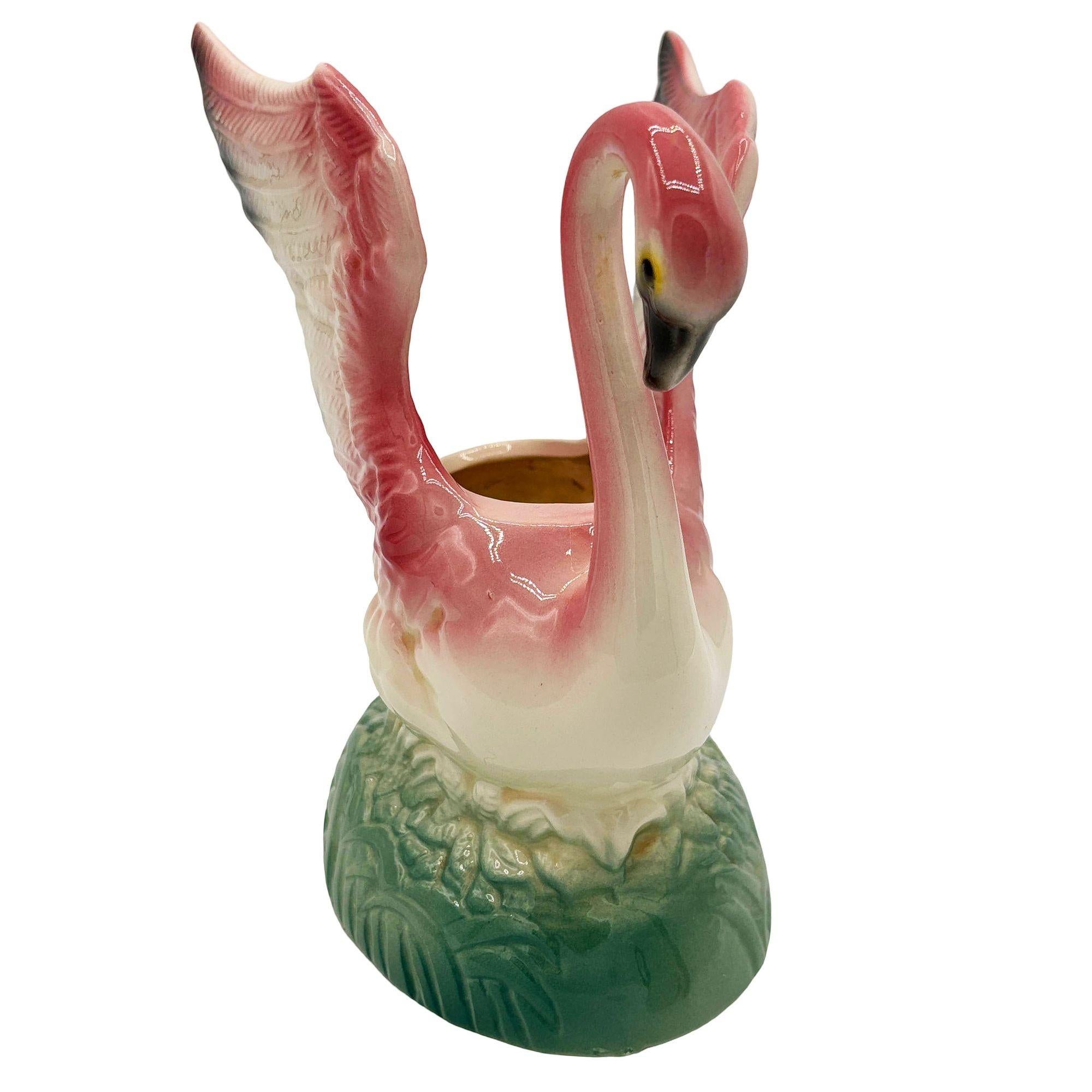 Mid-century pink and green California Pottery ceramic open-wing flamingo tabletop planter. The planter features a beautifully detailed pink flamingo landing on a light green grassy field. It comes in a gloss finish that highlights the rich pinks,