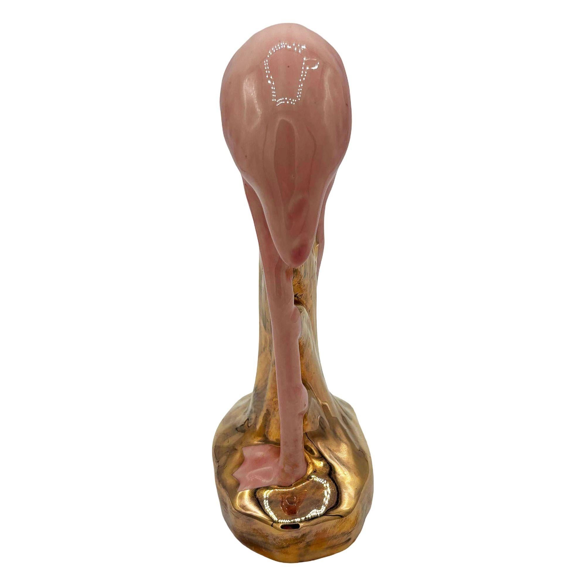 Statuetta di fenicottero in ceramica rosa e oro di metà secolo. La statua raffigurava un fenicottero rosa dalle lunghe zampe, una forma snella e alta in piedi su un campo erboso, che si inchinava per bere. La finitura lucida mette in risalto i