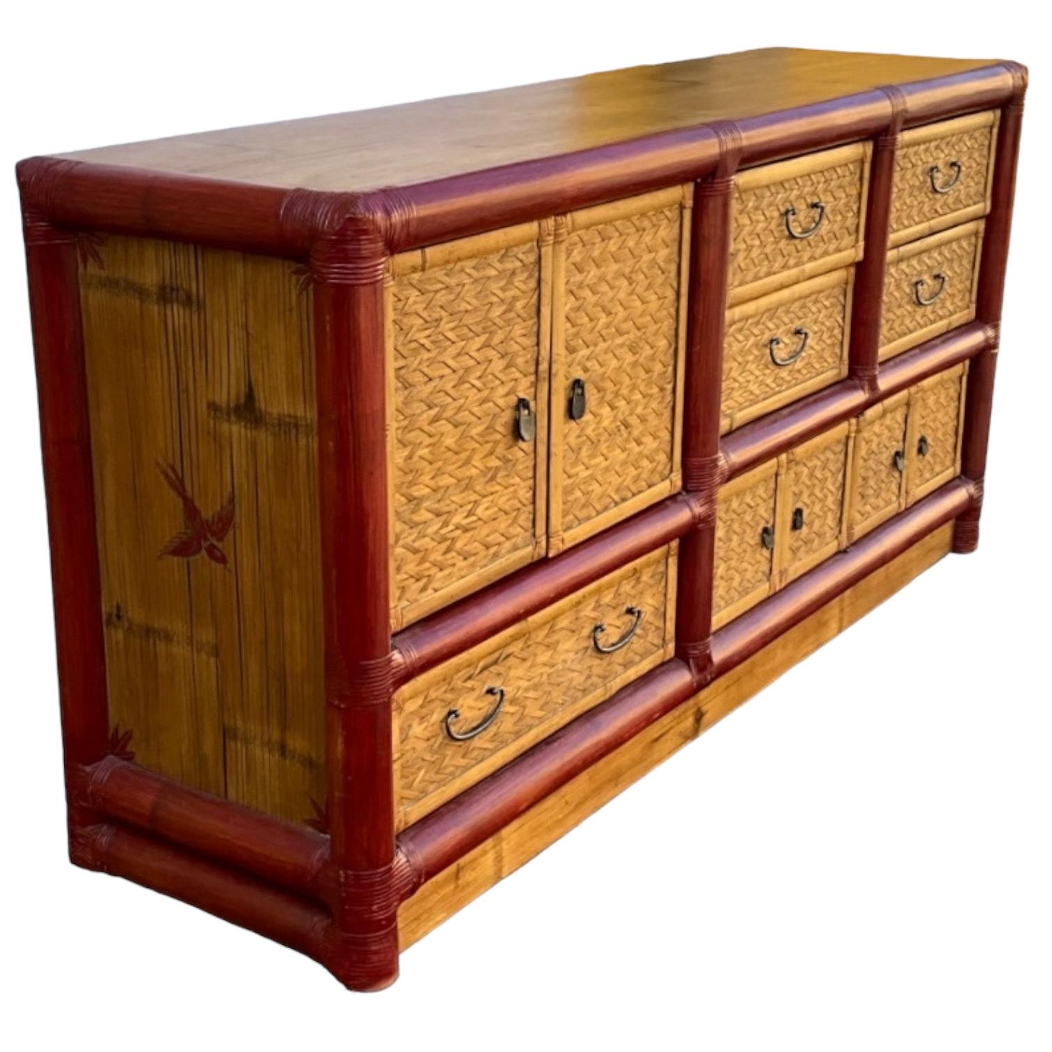 Si tratta di una credenza di grande effetto con un bel po' di spazio per la famiglia! Si tratta di una credenza in bambù di grandi dimensioni con uno stile Campaigner. È dipinto con una cornice rosso intenso e uccelli rossi. L'armadio ha una