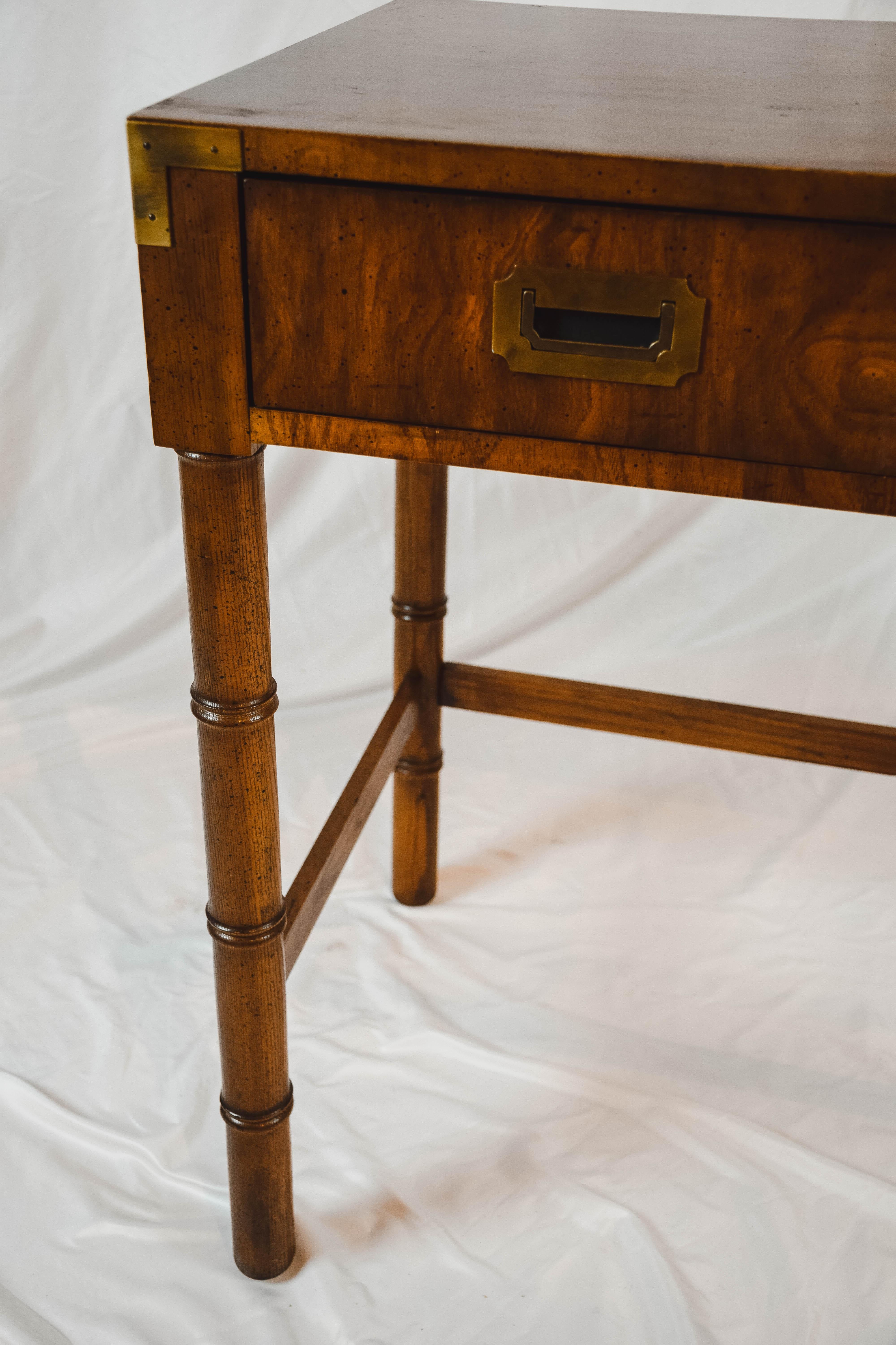 A Campaign style desk by Dixie Furniture, mid-20th century. This desk features a rectangular top resting on four legs with one drawer featuring brass hardware. Hallmarked Campaigner inside the drawer, this desk would add a touch of midcentury style