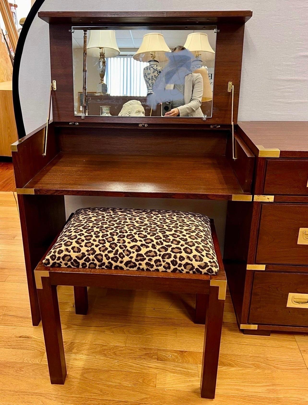 Vintage campaign style set features two-part construction consisting of a chest of drawers and vanity unit with flip-top mirror, paired with a matching stool. Features brass hardware and recessed brass pulls. Chest is attached to desk but can be