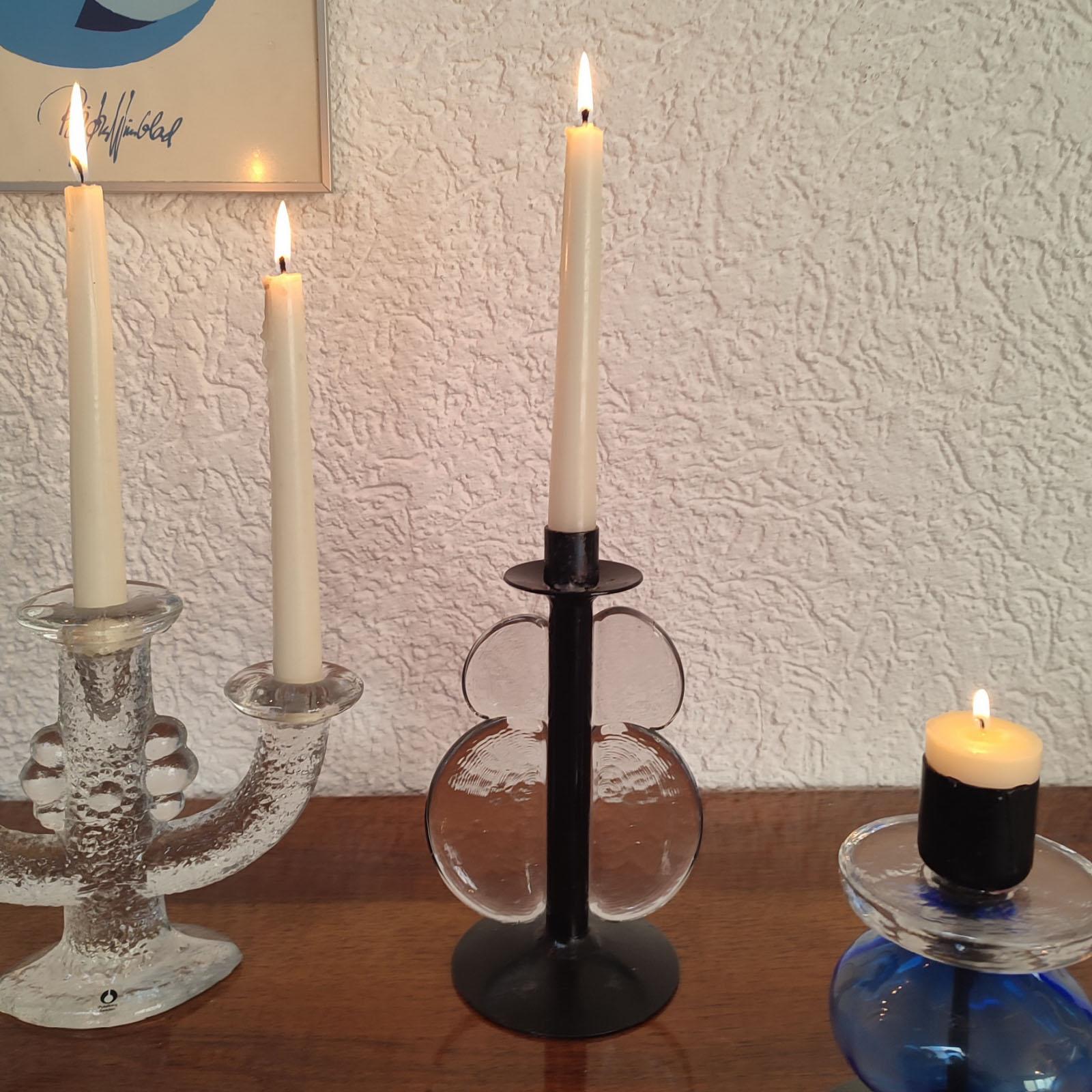 A unique candle holder made of black painted iron and transparent glass, in the well known style of Erik Höglund. The glass element decorate artistically de black painted iron stem, creating the stylized shape of a butterfly. For 2 cm candles. In a