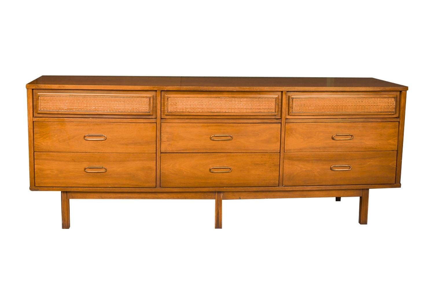 A beautiful mid-century long dresser with cane front drawer panels. Exceptional construction and style. This is a very simple yet modern 9 drawer design. Each drawer has beautiful walnut medium tones with attractive metal brass pulls. Top three