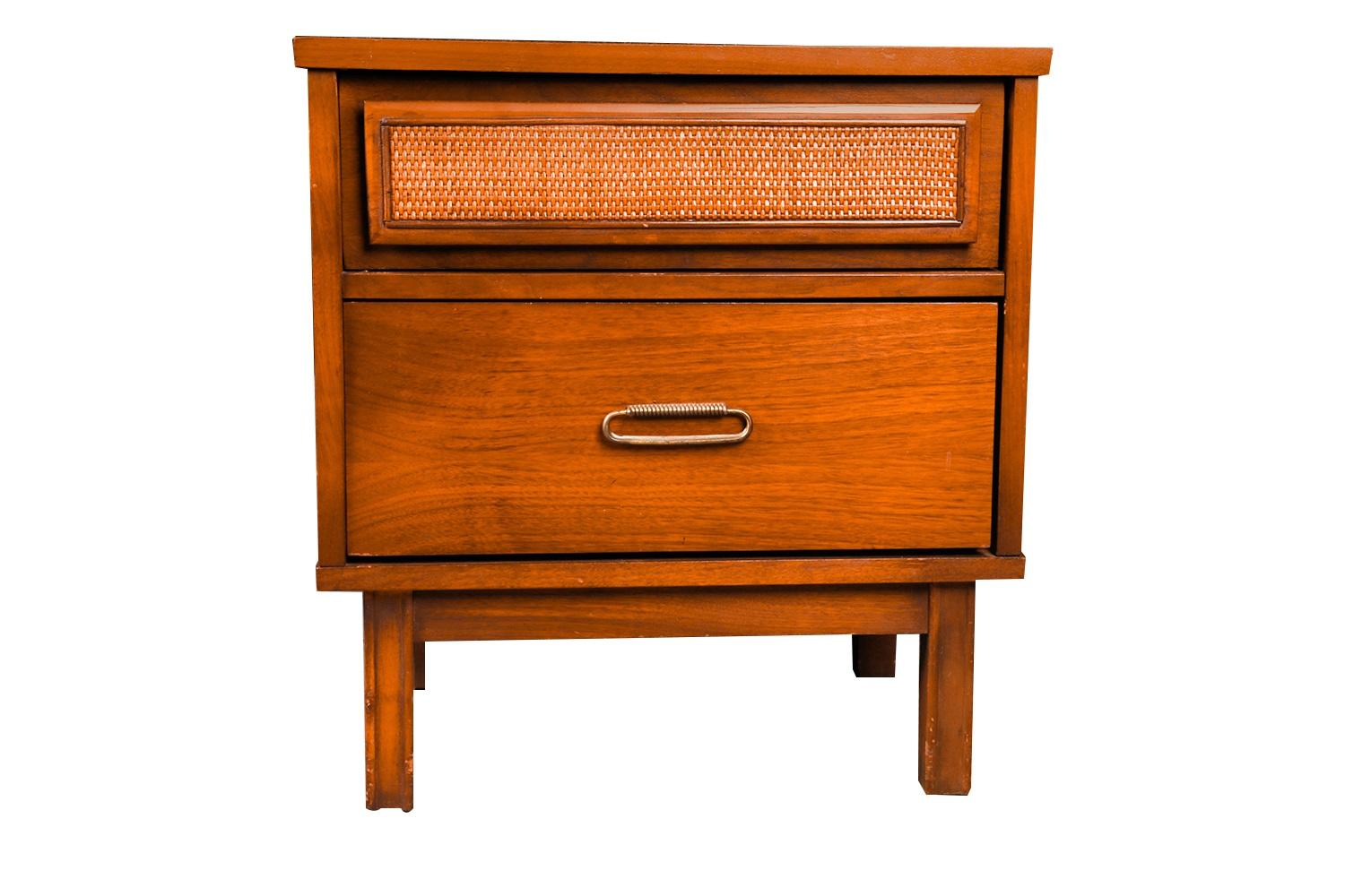 A beautiful mid-century nightstand/end table with cane front drawer panel. Exceptional construction and style. This is a very simple yet modern design. Features beautiful walnut medium tones with attractive metal brass pull. Drawer is accented with