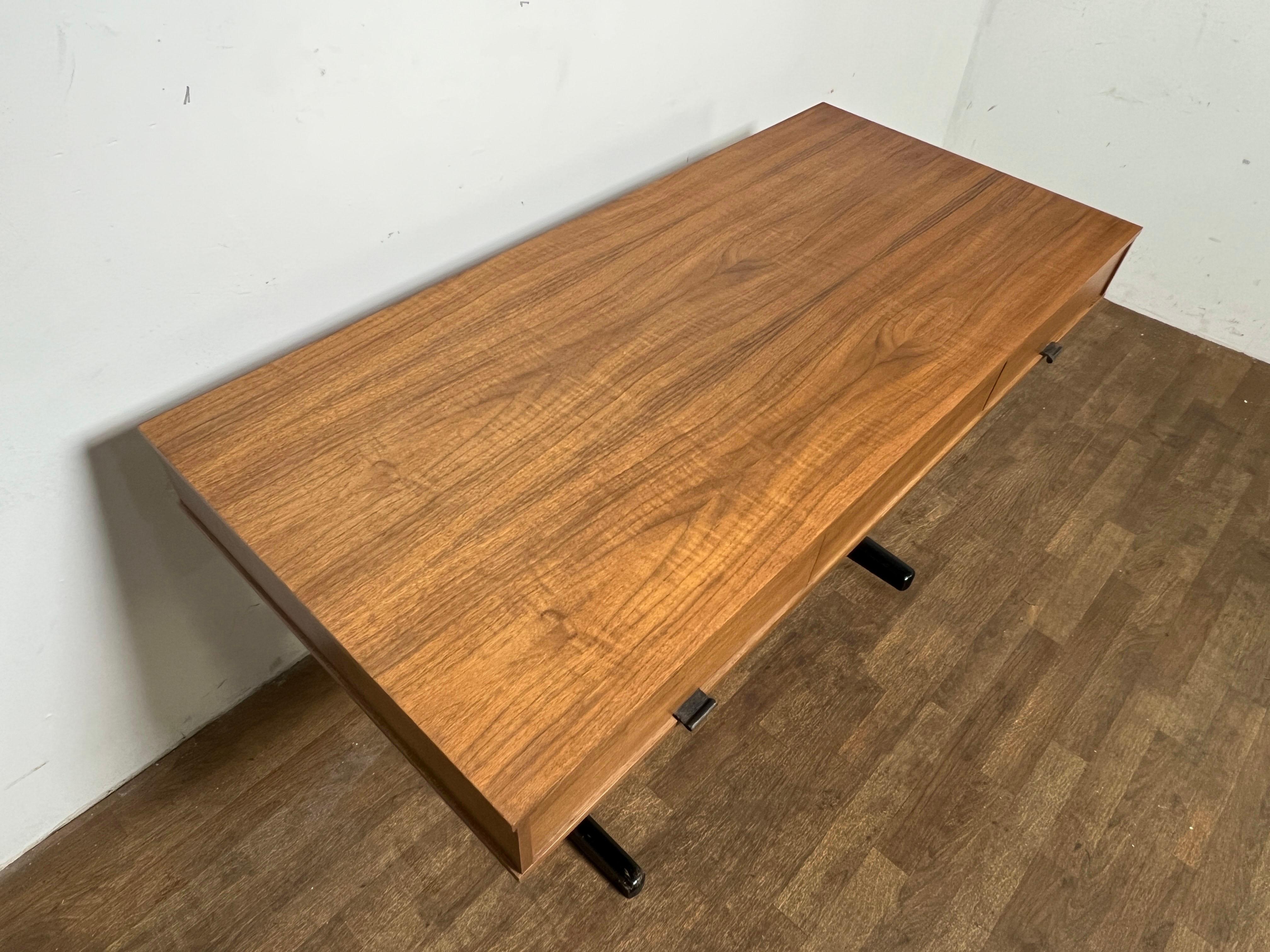 Bureau en porte-à-faux du milieu du siècle, avec plateau en teck et base laquée ébonisée, vers les années 1960. Deux tiroirs avec poignées en cuir présentent des intérieurs ébonisés avec des porte-stylos/crayons intégrés.  Non marqué, mais
