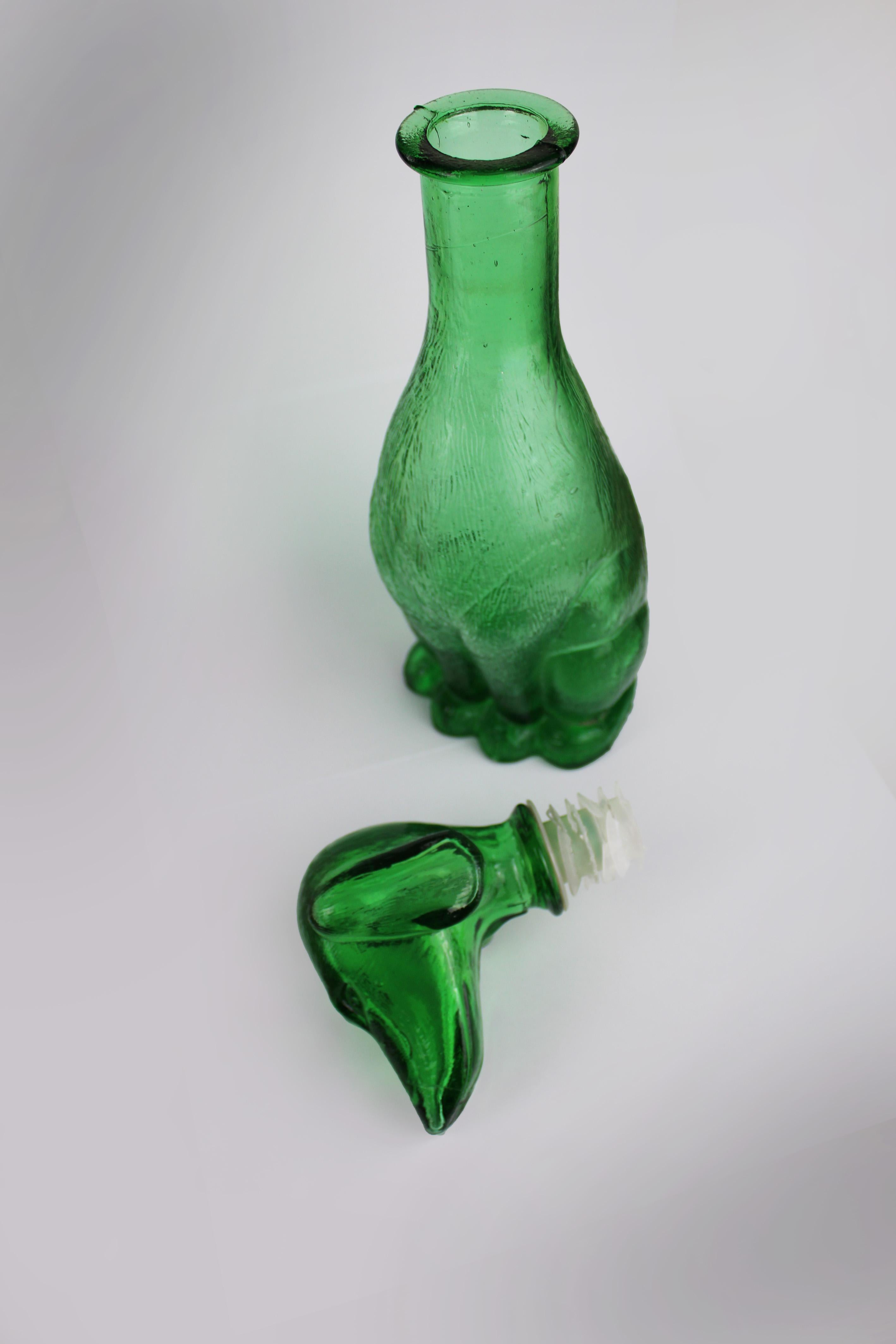 Add a touch of mid-century charm to your space with this stunning green embossed glass carafe from Empoli, Italy. Crafted in the 1960s, this unique piece features a playful dachshund, merging functionality with whimsy and Italian style. Perfect as a