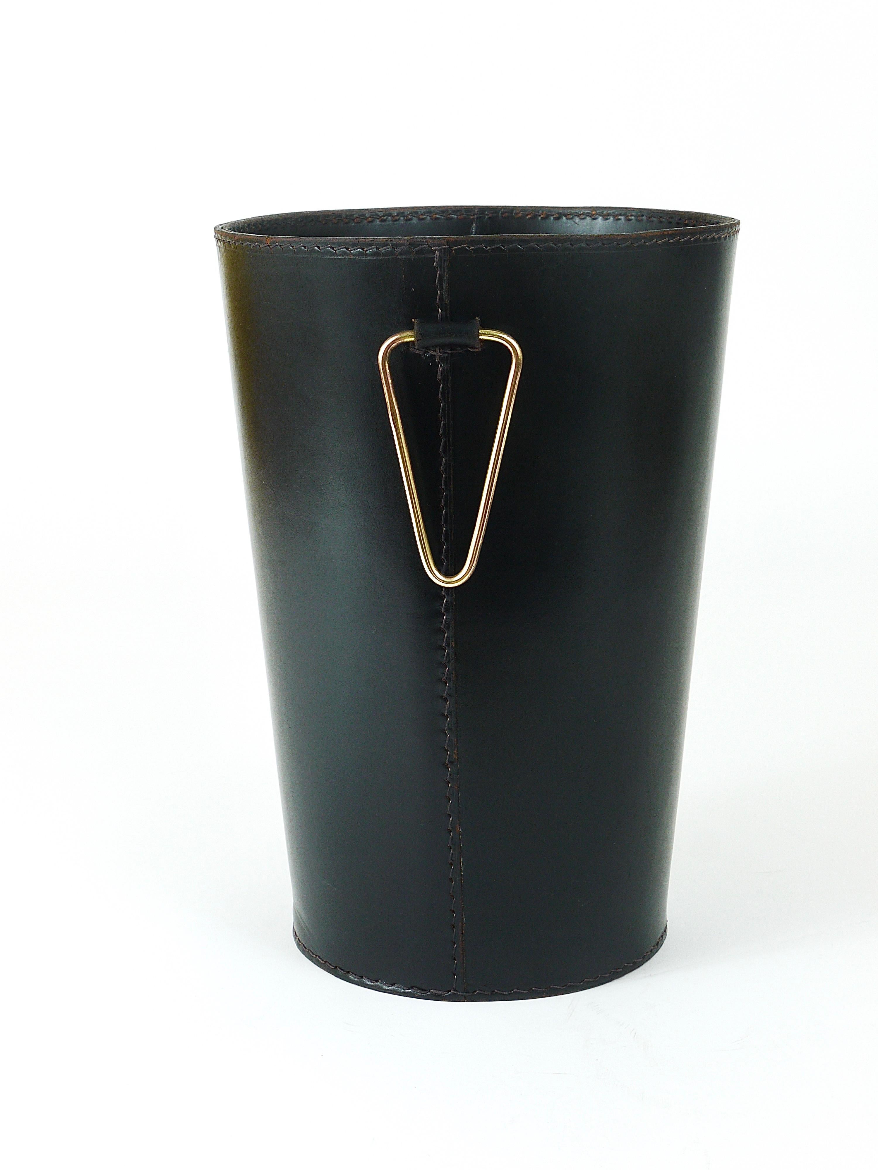 A beautiful and elegant, vintage Mid-Century Modern paper basket / paper bin from the 1950s. Designed an executed by Werkstätte Carl Aubock, Vienna / Austria. Handmade and hand-sewn from thick black leather, decorated by a polished brass handle. 