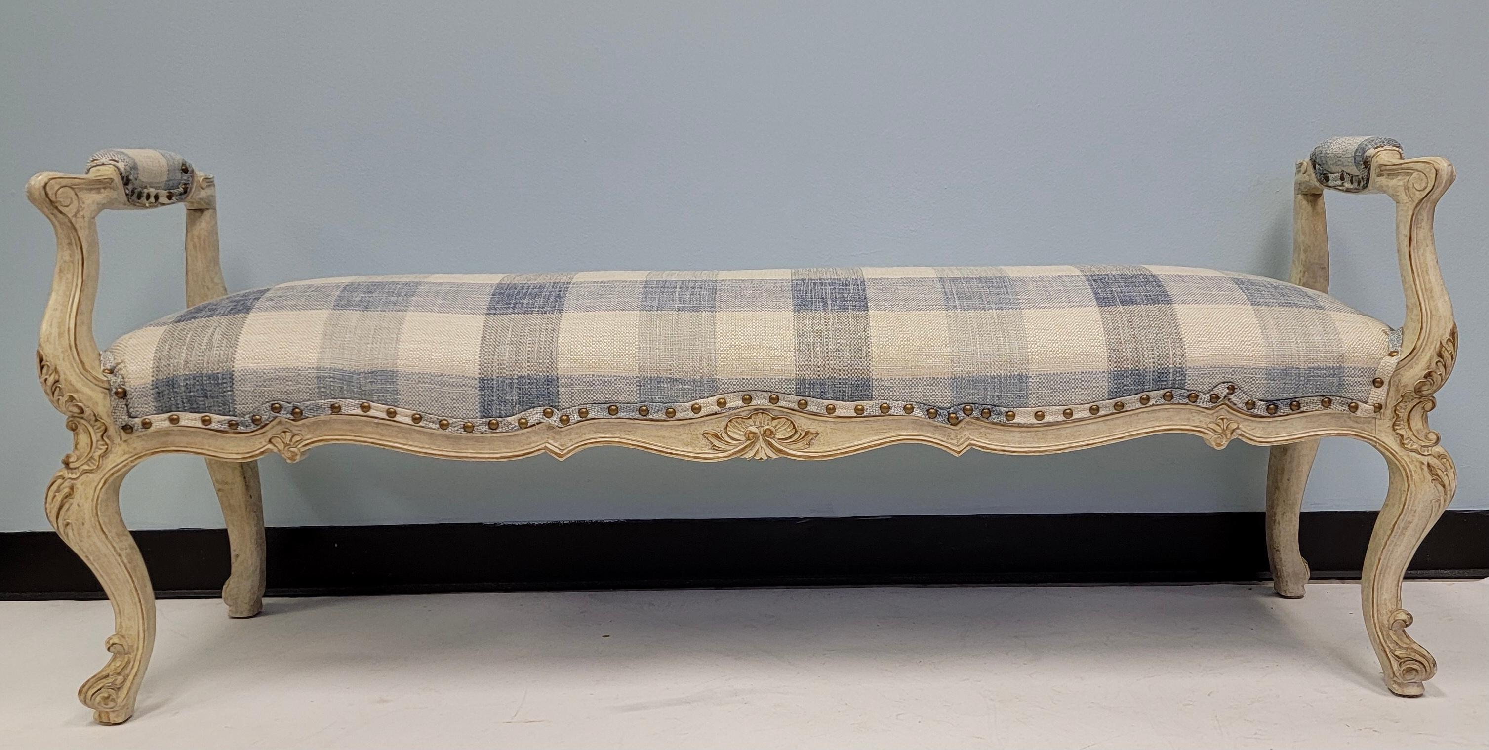 This is a lovely carved and painted French style bench upholstered in a blue and white textured linen blend upholstery. It is attributed to Lewis Mittman.