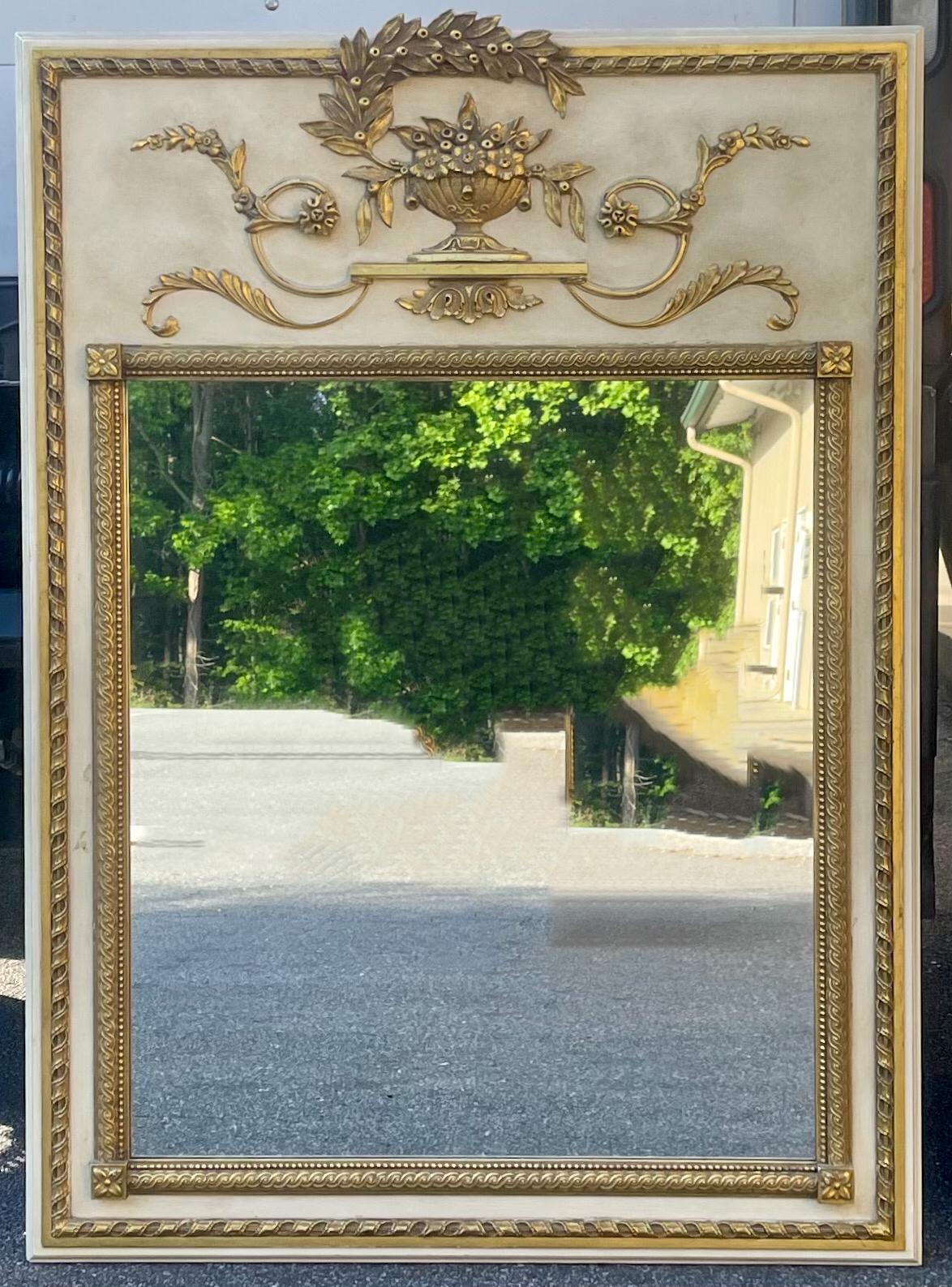 This is a lovely painted and carved giltwood mirror by Milch & Son. It has carved giltwood foliate creating a trumeau effect. It is marked with a partial label.