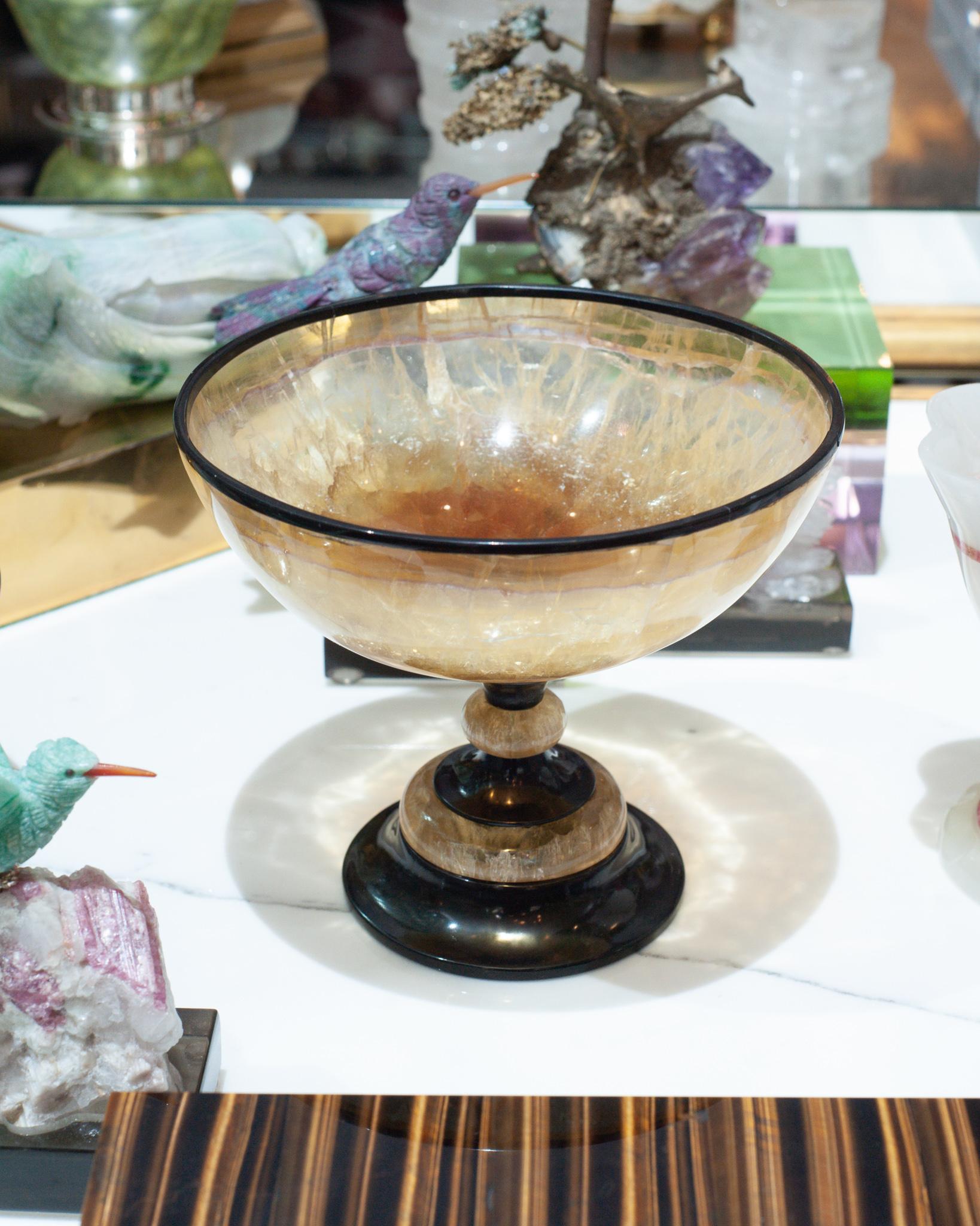 A stunning mid-century bowl, carved from gold tone fluorite, and enhanced with a rim and base of natural black onyx. An exceptional and rare quality of fluorite -this marriage of craftsmanship and natural mineral specimens create a luxurious and