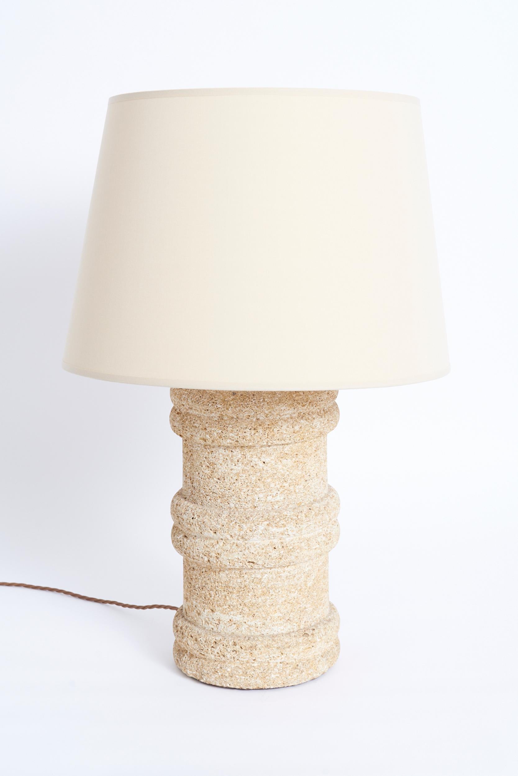 A carved tuff stone table lamp
France, Circa 1970
With the shade: 66 cm high by 45.5 cm diameter 
Lamp base only: 43.5 cm high by 22 cm diameter 
