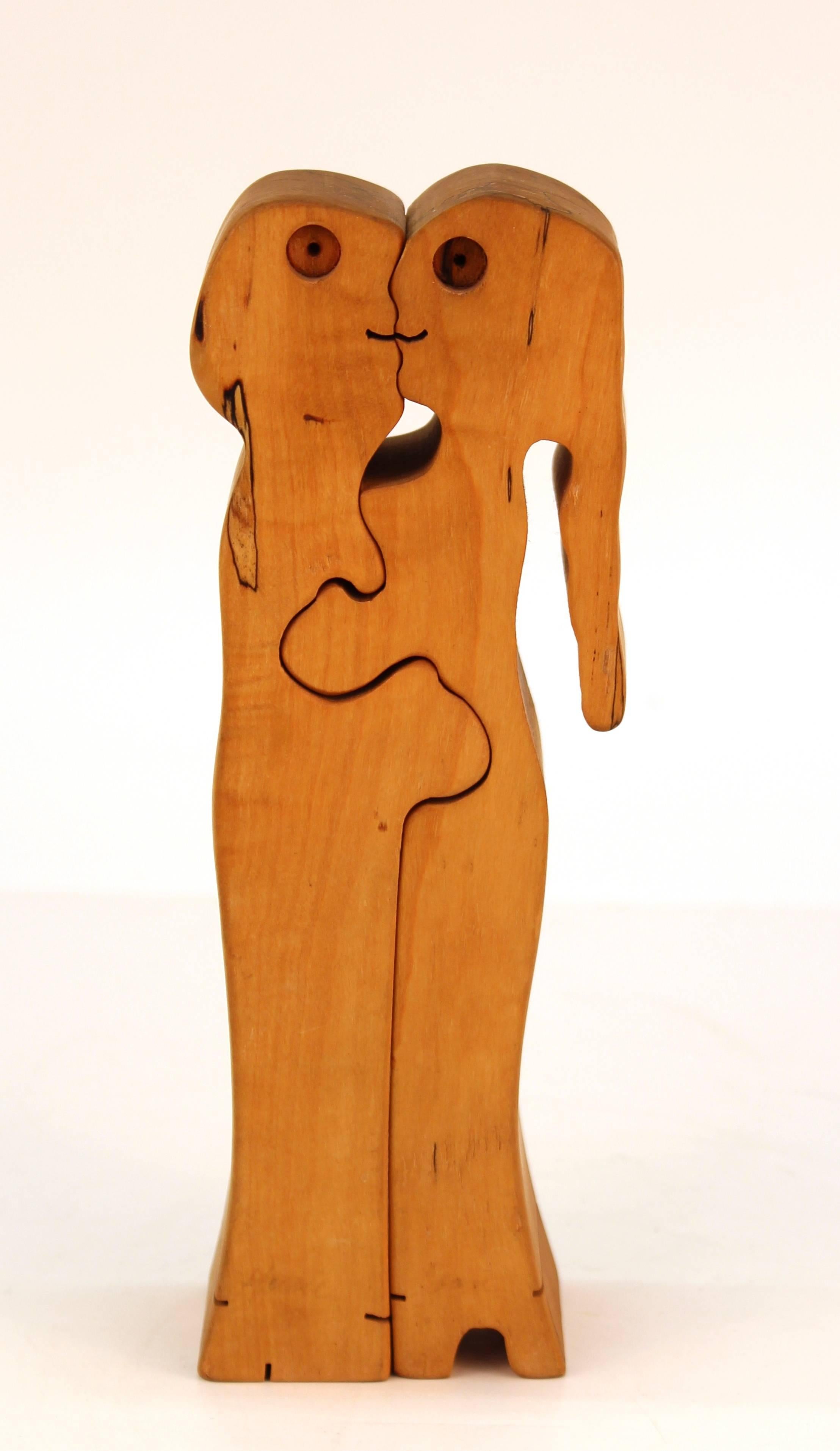 A Mid-Century Modern puzzle sculpture made of carved wood depicting an embracing couple. The two pieces are interlocking and detach. The item was made in the 1970s and is in great vintage condition.