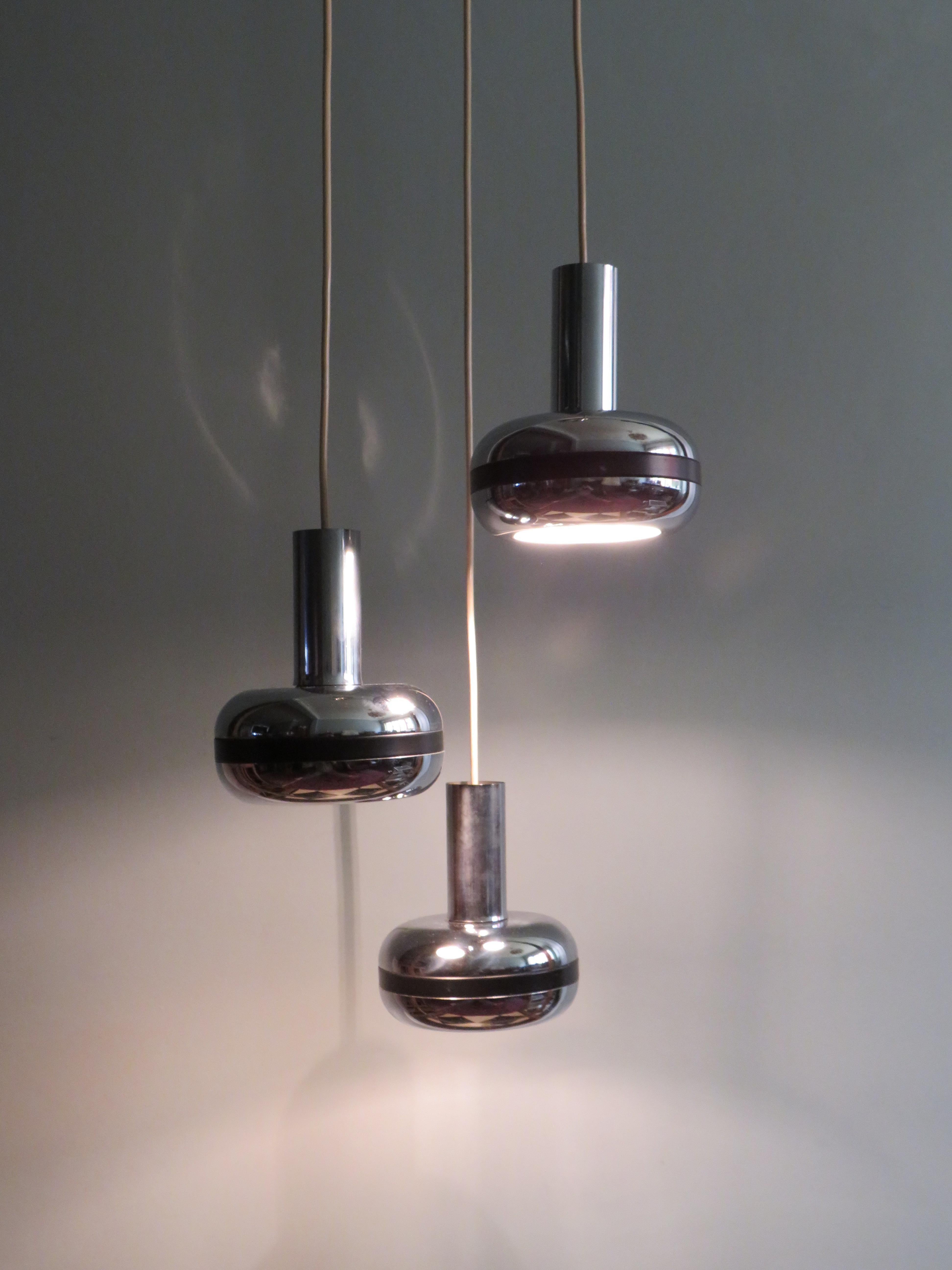 Pendente a cascata con 3 globi cromati anni '70.
Il ciondolo a cascata è dotato di 3 globi cromati con un dettaglio nero intorno e una piastra da soffitto a forma di corno.
L'altezza dei tre globi può essere regolata individualmente e ognuno di