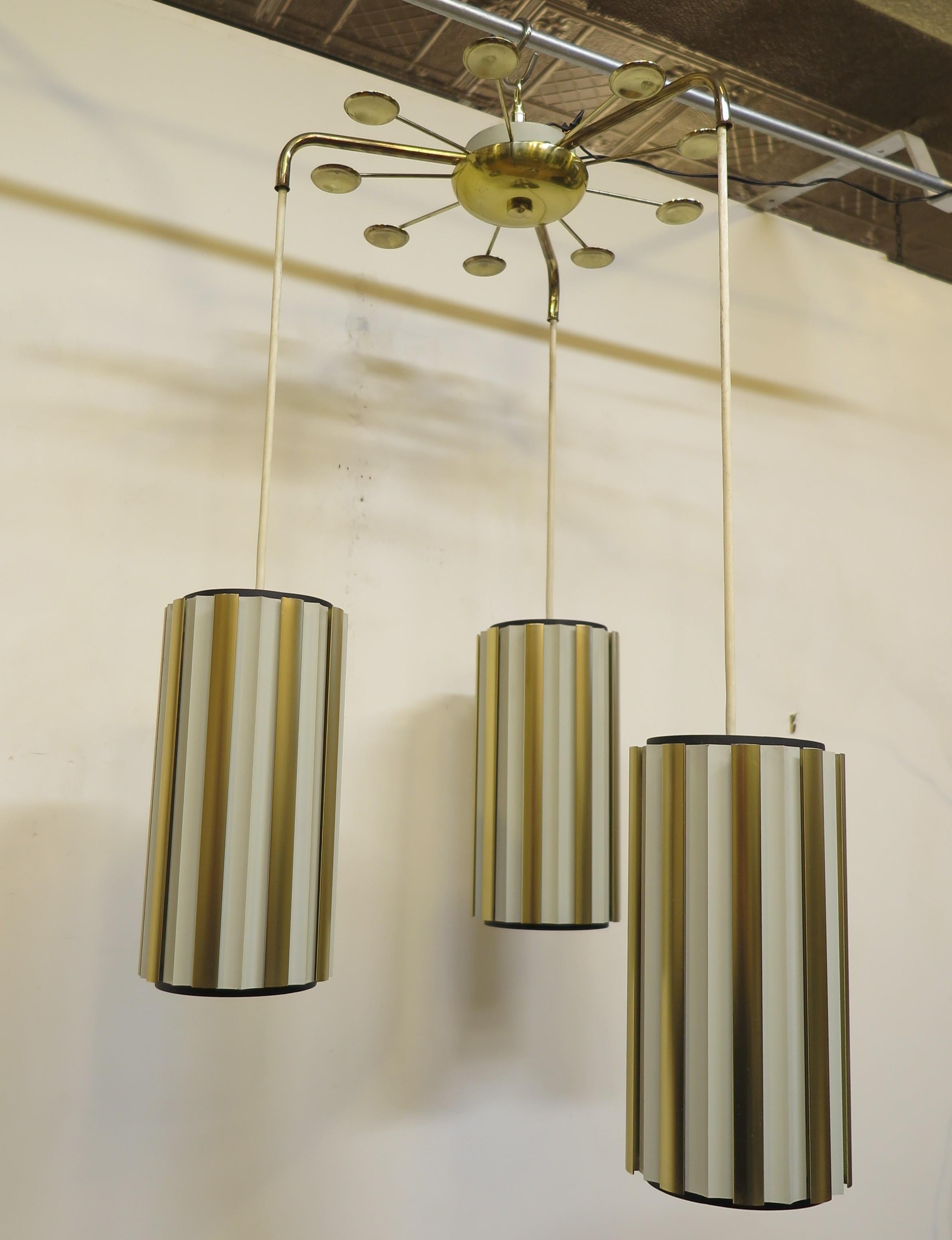 Mid-century cascading pendant chandelier by Lightolier attributed design  Gerald Thurston.  Three cascading hanging pendants of aluminum flange ribs vertically overlapping each other to form tall slotted cylinders. The cylinders are designed to