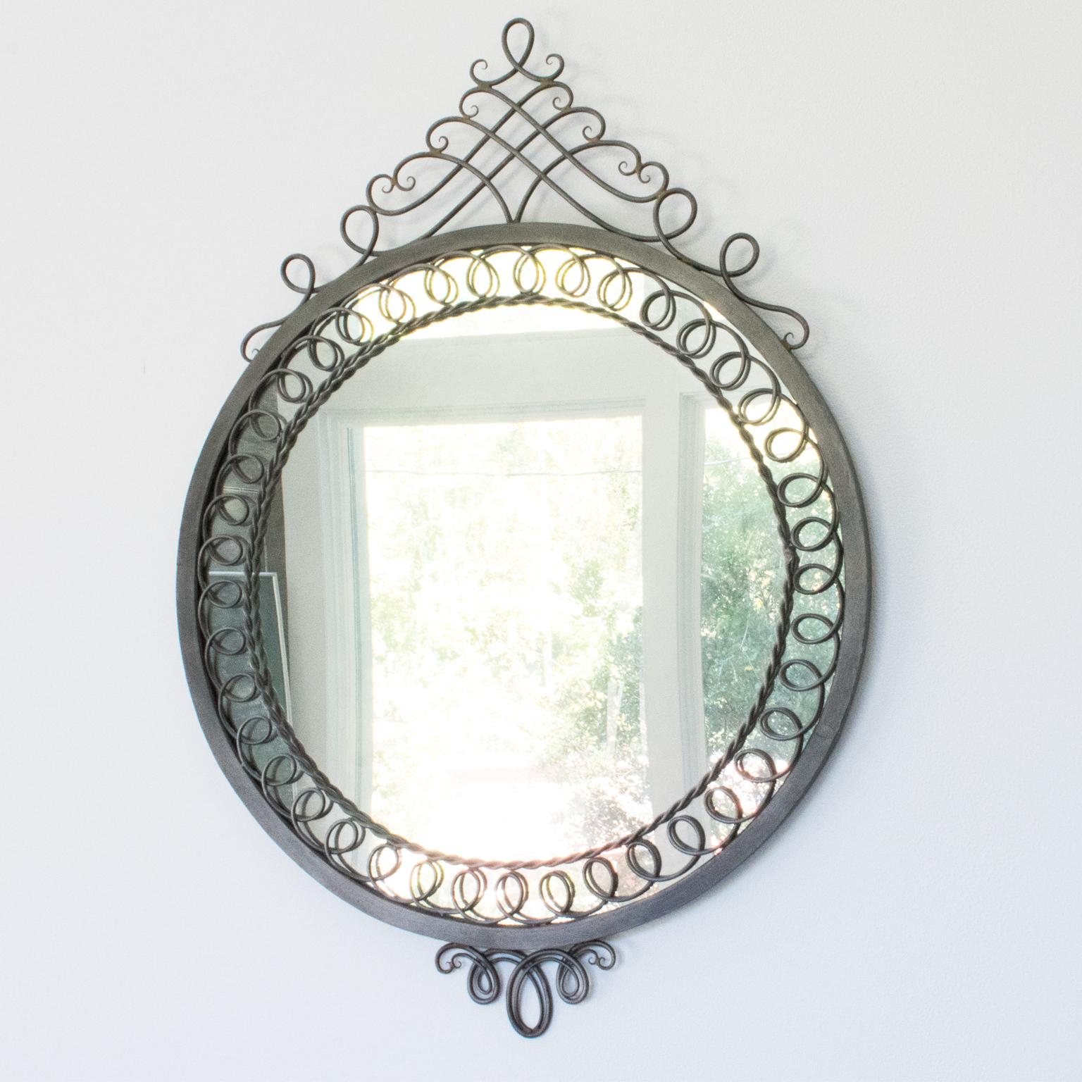 This striking French 1950s Mid-Century neoclassic cast iron wall mirror is a timeless piece of home decor. Its impressive rounded shape is surrounded by ornately detailed metal framing, finished with a beautiful original gunmetal patina. The lack of