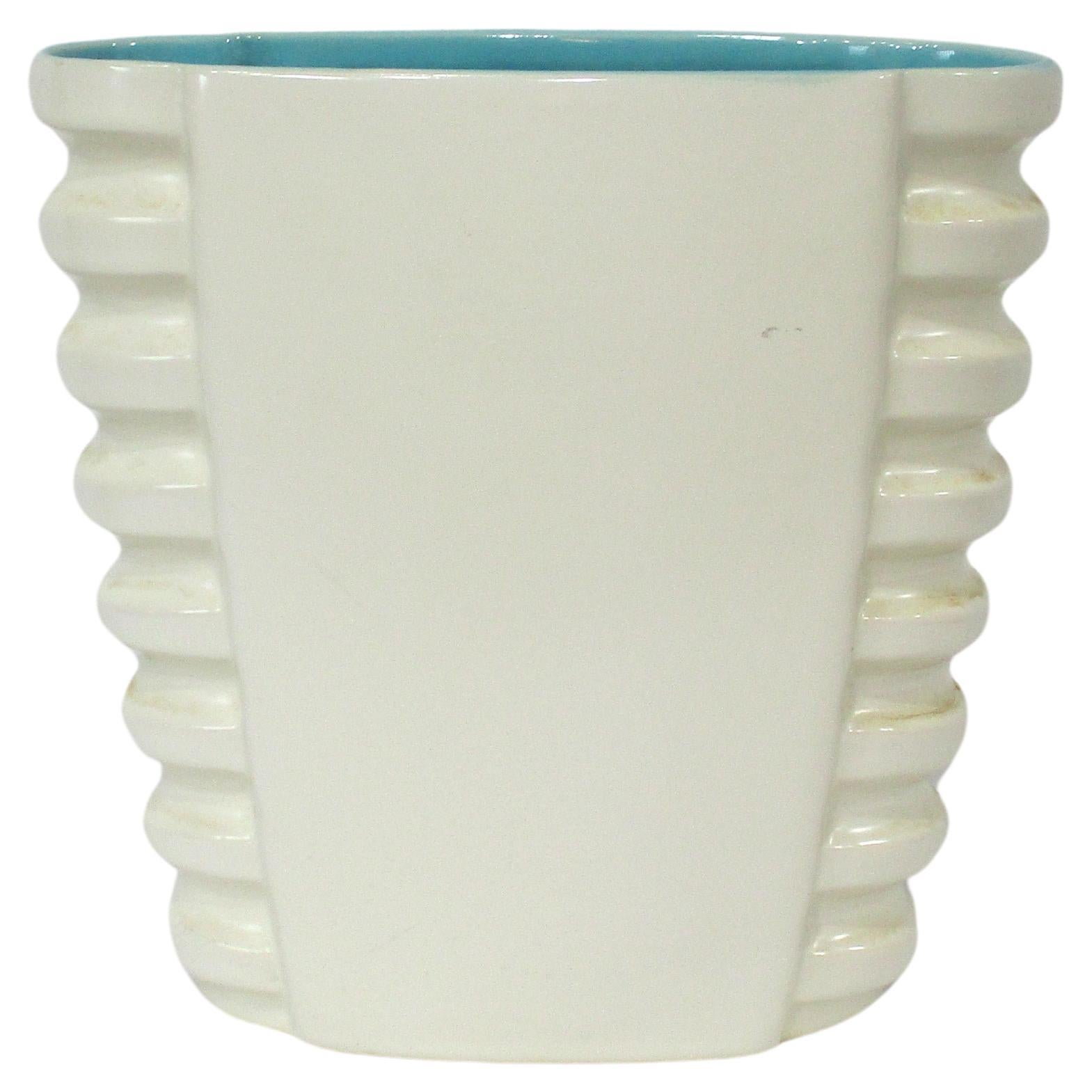 A very nice ribbed Mid Century vase with buttery smooth off white glaze and a turquoise interior . Crafted by the Catalina Pottery company located on Catalina Inland but moving manufacturing to the GMB Pottery company California . The vase can work