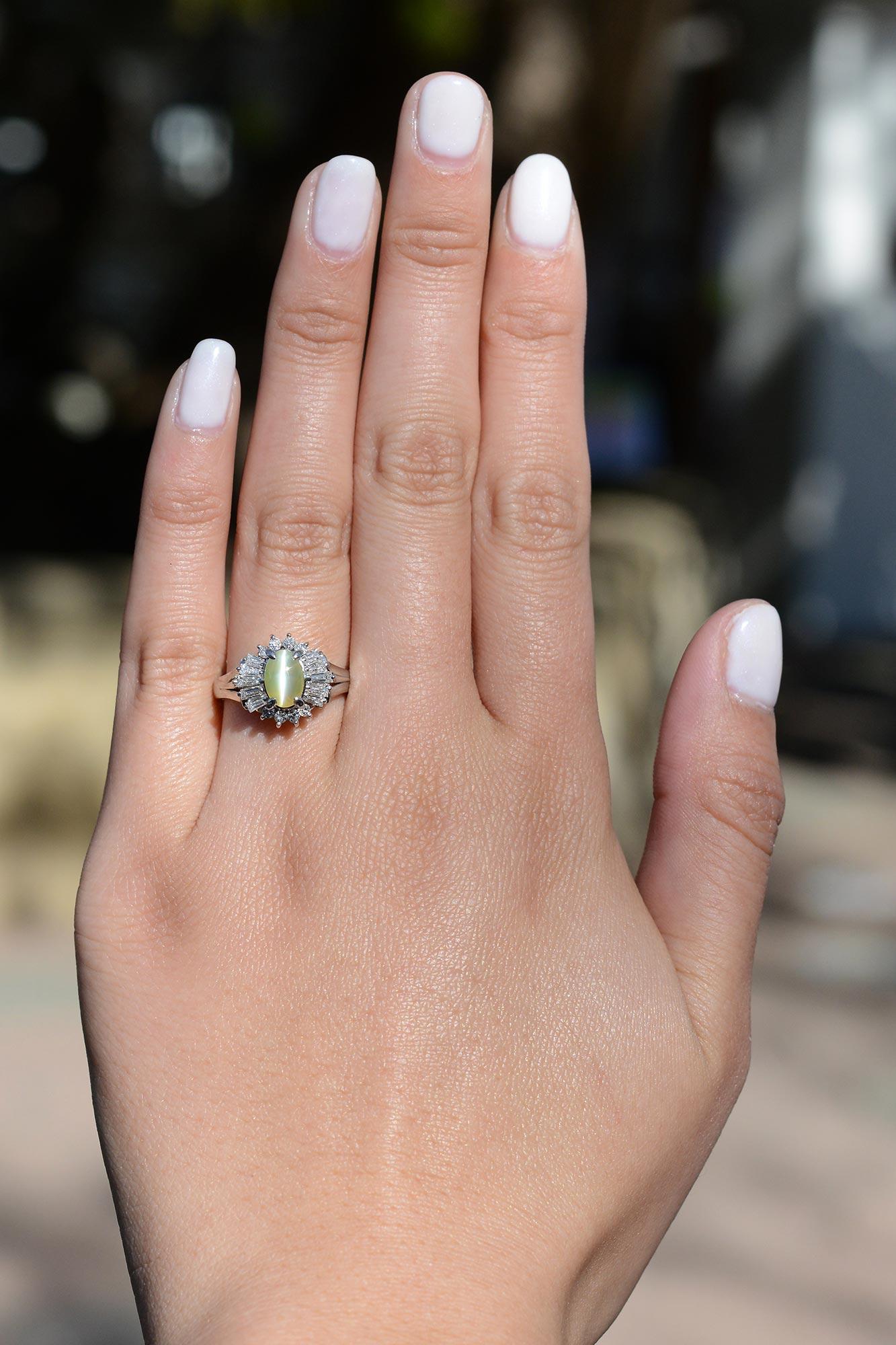 A classic mid century estate ring with a compellingly hypnotic center gemstone. This captivating cat's eye chrysoberyl displays a striking natural phenomenon that is extremely rare. A wonderful soothing green color along with a creamy flash pairs