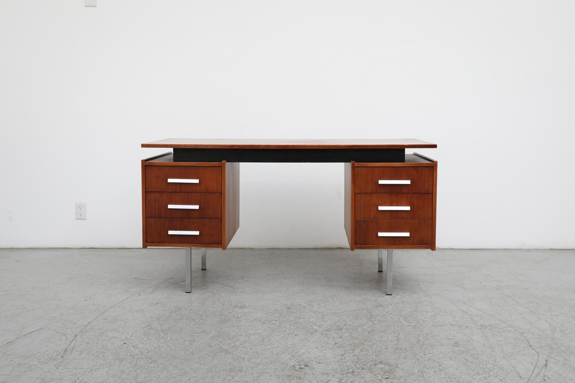 Mid-Century office desk designed  and manufactured by Dutch manufacturer Tijsselling. The desk is made of  teak with a floating top and a black painted wood riser. Three sliding drawers on each side with aluminum pulls and chrome legs. In original