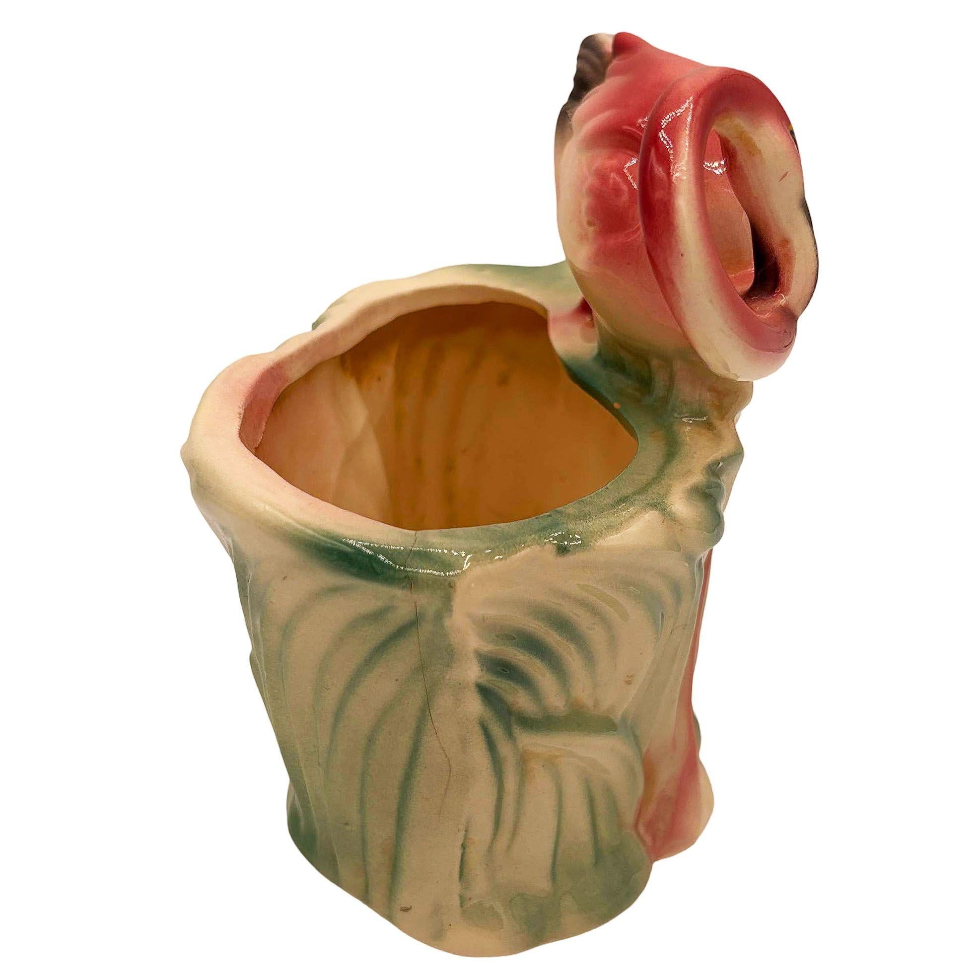 Mid-century pink and green ceramic flamingo tabletop California pottery tabletop planter. The planter features a beautifully detailed pink flamingo resting on a lush green grassy field. It comes in a gloss finish that highlights the rich pinks,