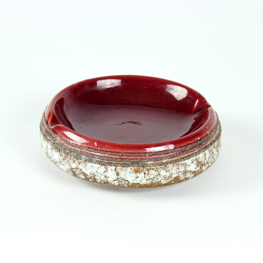 Beautiful piece of mid-century design. This is a ceramic ashtray in an elegant design and an interesting color combination. Deep dark reds in glaze finish are mixed with the brown and rough surface. The mixture of materials makes the ashtray easy to