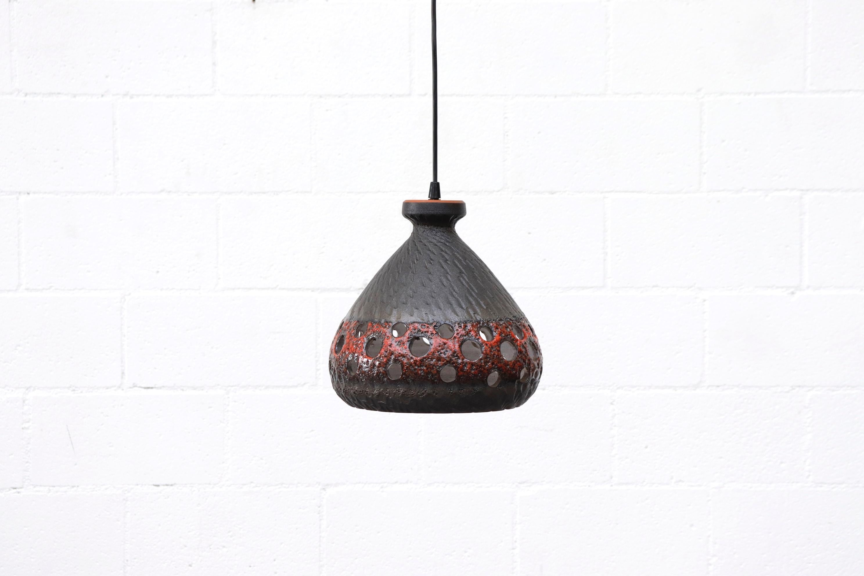 1970s midcentury MOD ceramic bell pendant lamp with circle cut-outs for Ambient light. Outside is charcoal grey with red lava glaze, and the inside is a natural bone white glaze. Uses regular light bulb. Original condition. Other various ceramic