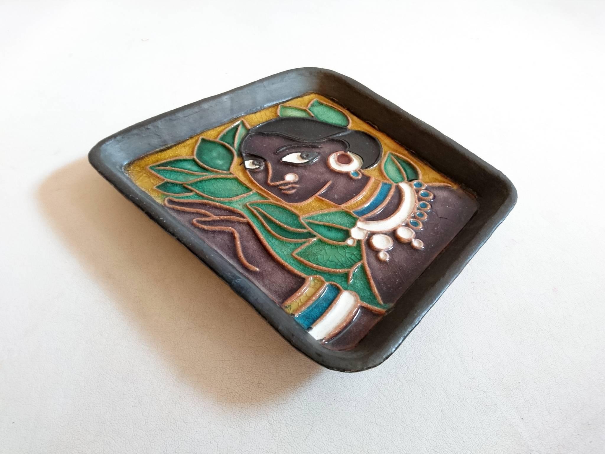 Irregular shaped charger like bowl depicting an exotic beauty. Marked on the back in the glaze TAKA-PUKA and on a sticker attached to the back: B.H.I.A, TL w/6, wall plaque, Rs 22/50.