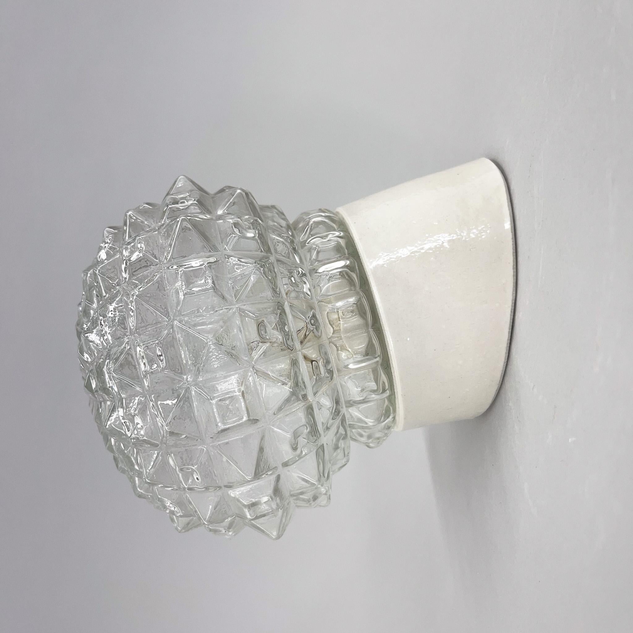 Vintage wall light with ceramic base and lamp shade made of clear pressed glass. New wiring.