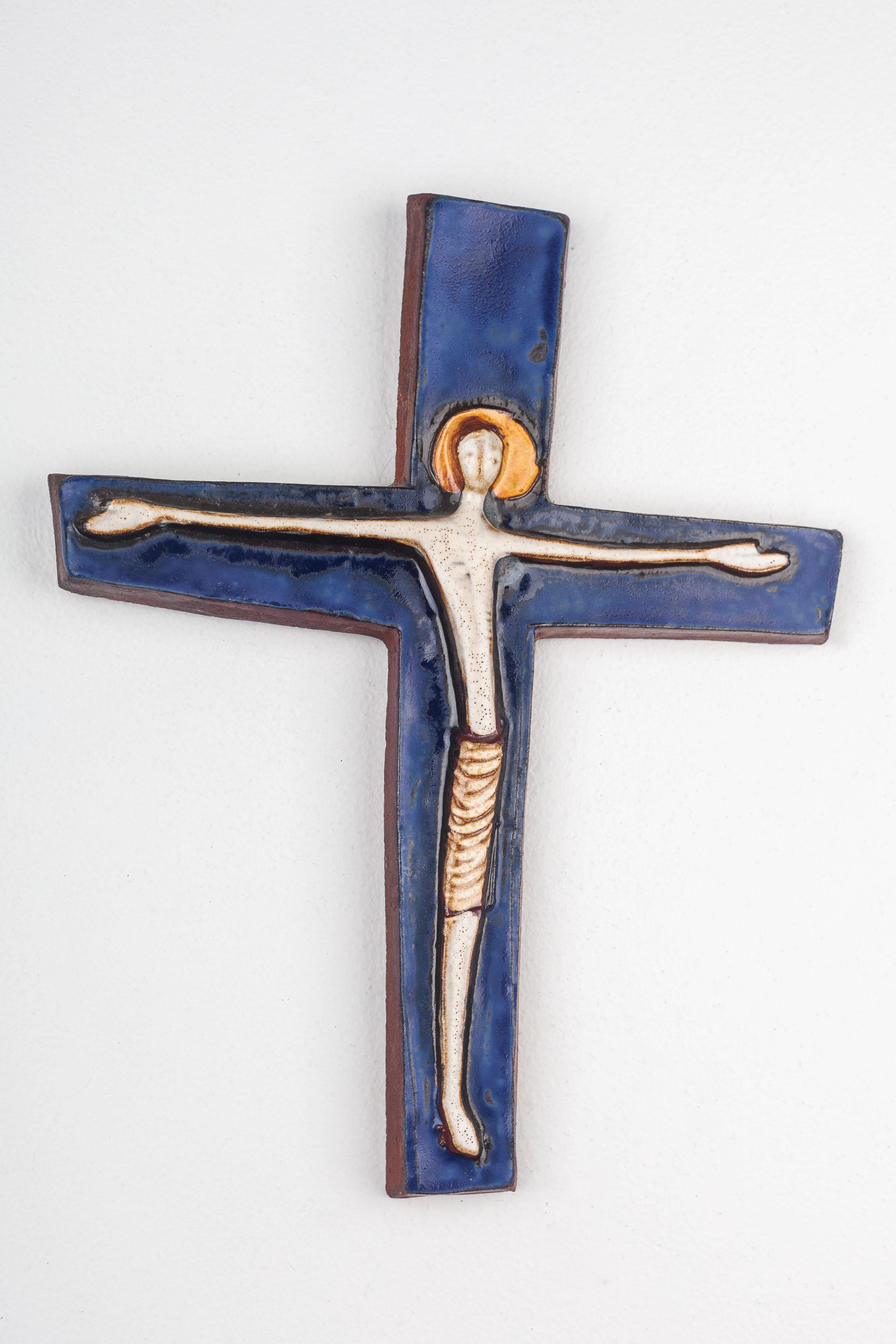 This solemn and evocative ceramic crucifix is a representative work of mid-century modern religious art, handcrafted by a European studio pottery artist. The figure of Christ is depicted in a minimalist style, rendered with an emphasis on line and