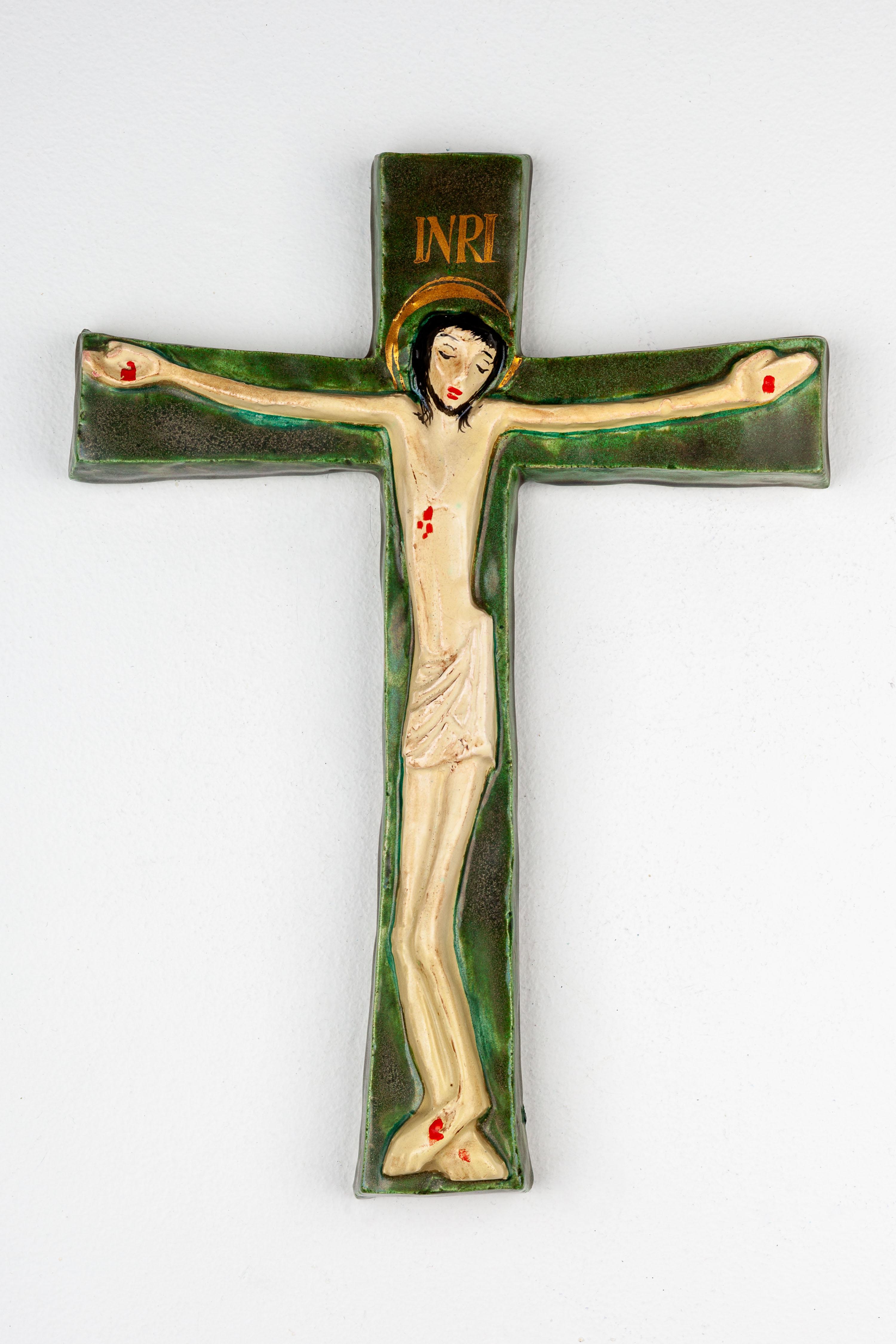 This ceramic crucifix is a distinctive artifact of mid-century European studio pottery, highlighting the period's unique blend of traditional religious motifs with modern artistic sensibilities. The figure of Christ is sculpted in a simplified,