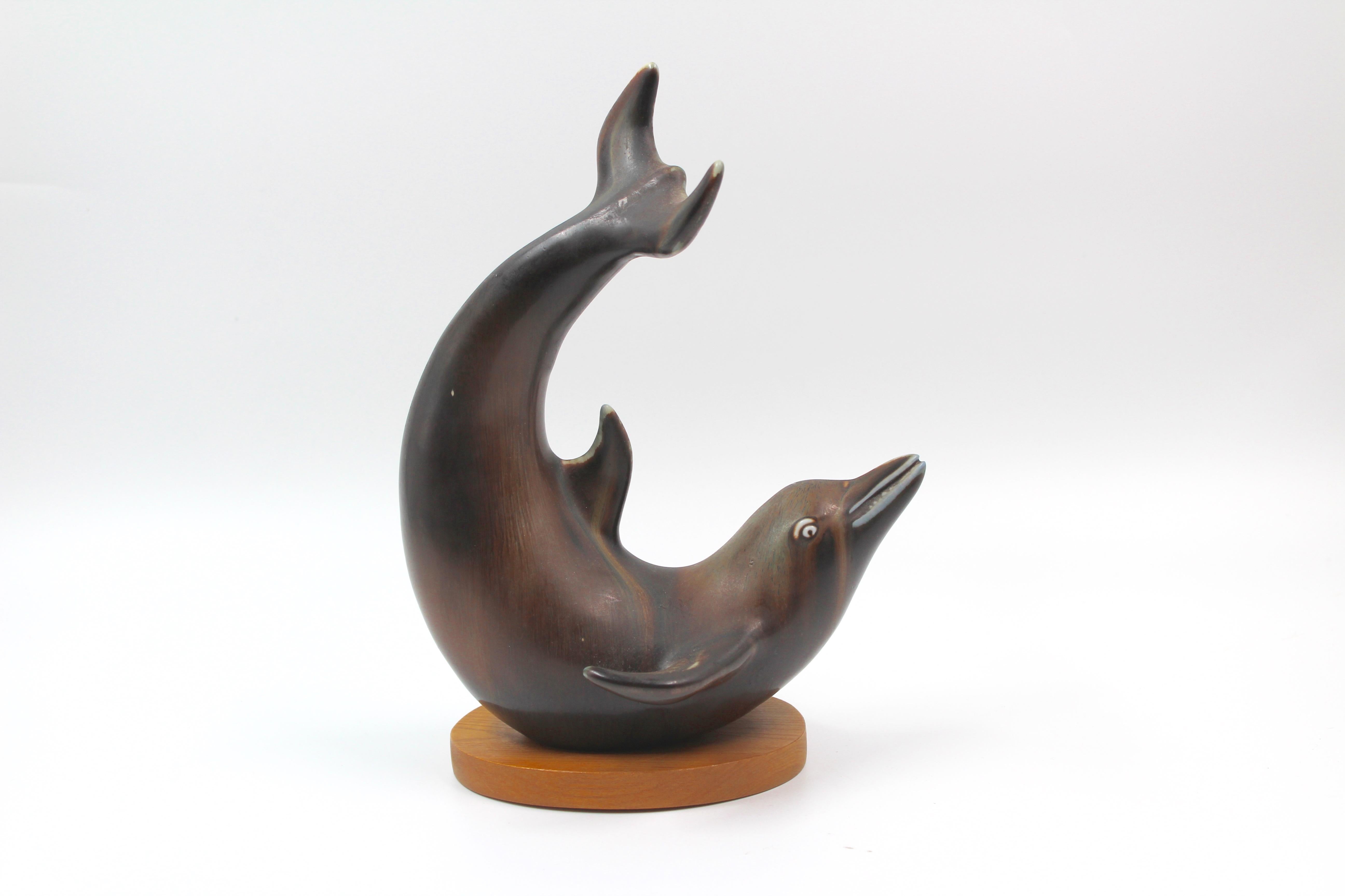 A very decorative ceramic dolphin with beautiful glaze, designed by Gunnar Nylund in the 1950s and produced by Rörstrand. The piece comes with the original wood plate and is in excellent condition.