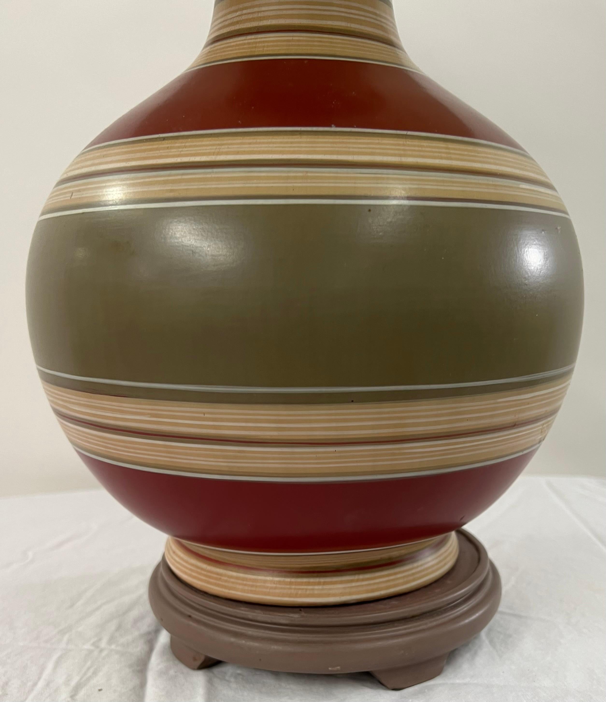 A Mid-Century ceramic table lamp. The lamp body is finely handprinted in beautifully earthy tone colors or green, beige and burgundy and comes with its original shade. There is a small chip on the ceramic as seen on the 4th Photo of the listing. The