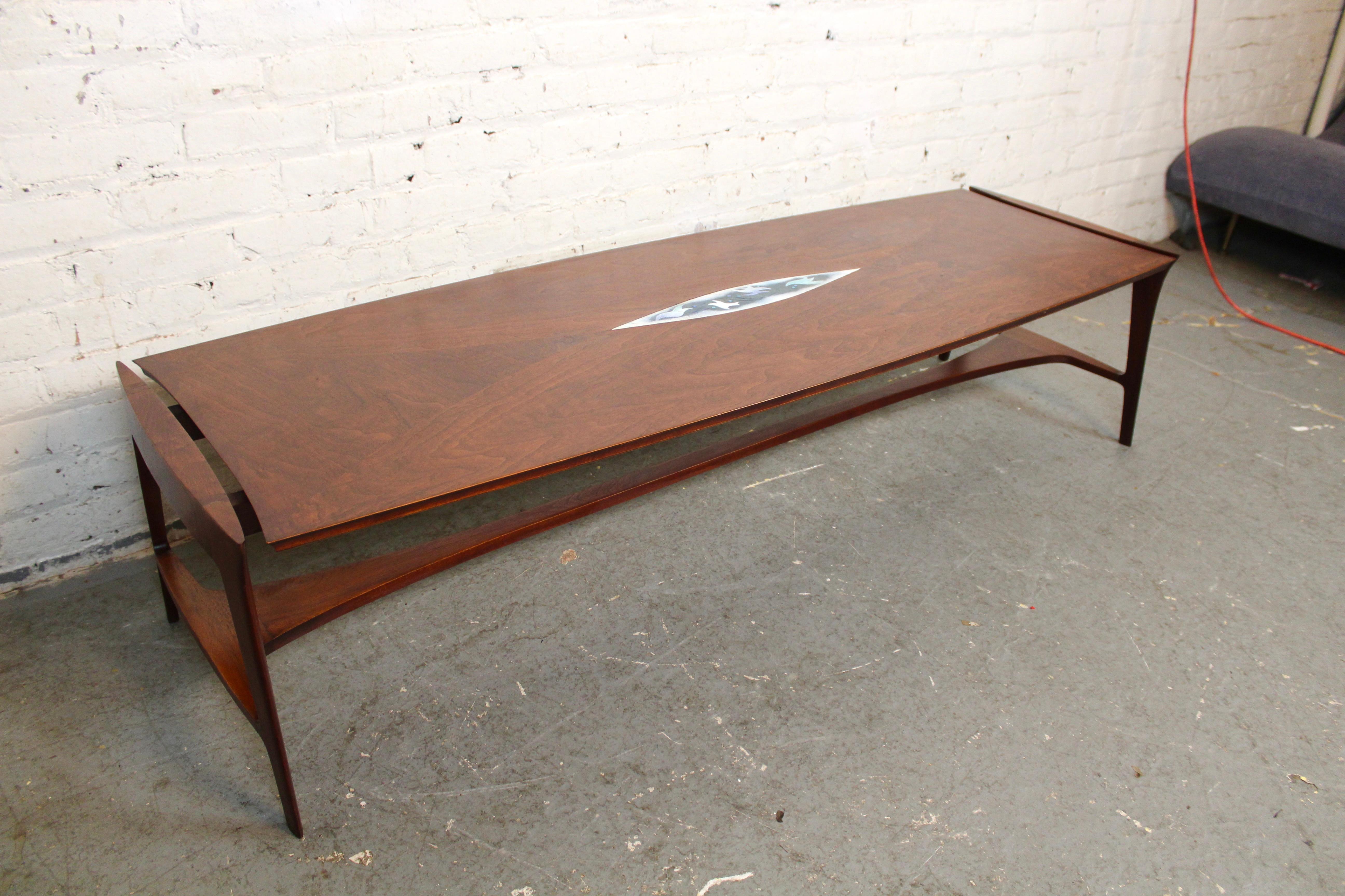 Envolez-vous dans un décor vintage avec cette merveilleuse table basse du milieu du siècle, ornée d'une incrustation d'oiseaux en carreaux de faïence. Construit pour John Stuart de Grand Rapids en noyer et en chêne robustes, la teinture cerise