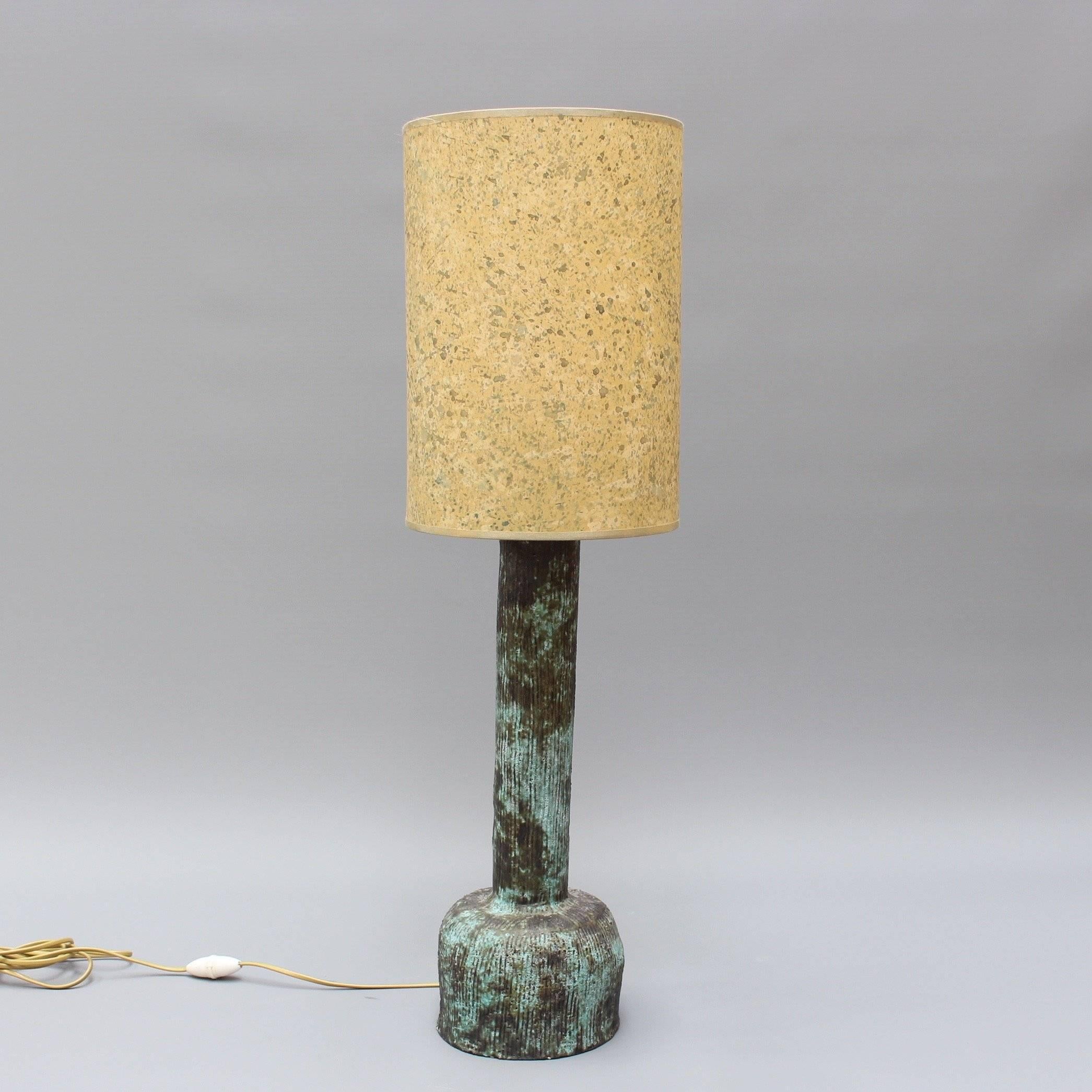 Midcentury ceramic lamp (circa 1960s), by an unknown French ceramicist. Tactile lines are etched on the surface of this imposing but elegant lamp. It has a bulbous base and a trunk like a Roman column - almost verdigris in appearance. The creator