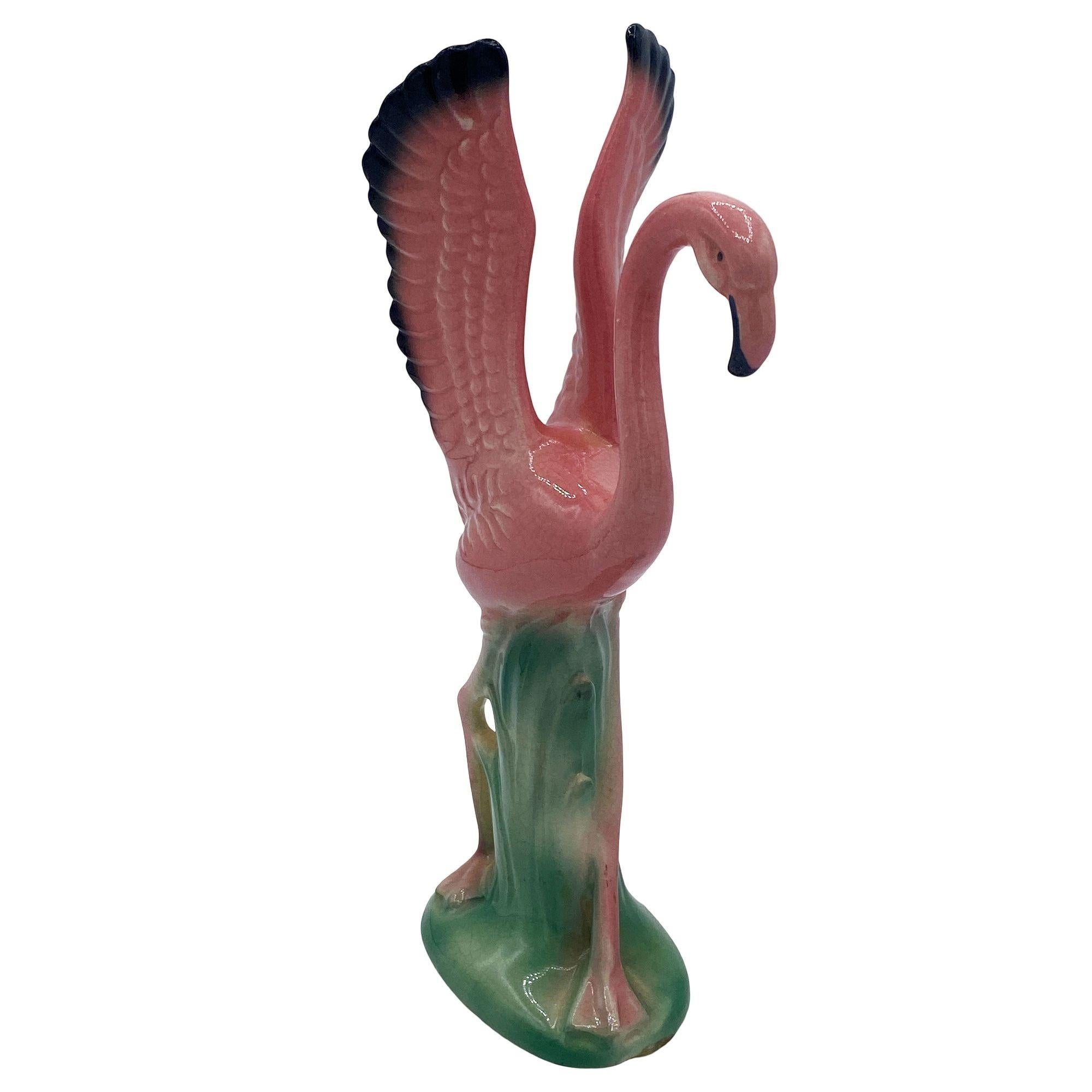 Mid-century pink and green ceramic flamingo statue set by Leftons. The set features two beautifully detailed pink flamingos in mid-flight, landing on lush leaves and grass. Each comes with a gloss finish that highlights the rich pinks, greens, and