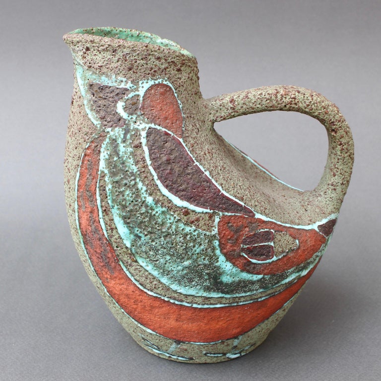 Stylised mid-century ceramic pitcher by Accolay (circa 1960s). A creative take on the traditional pitcher with extended handle, the zoomorphic shape suggests the very bird that is painted on the sides of its earthen brown form. The interior viewed