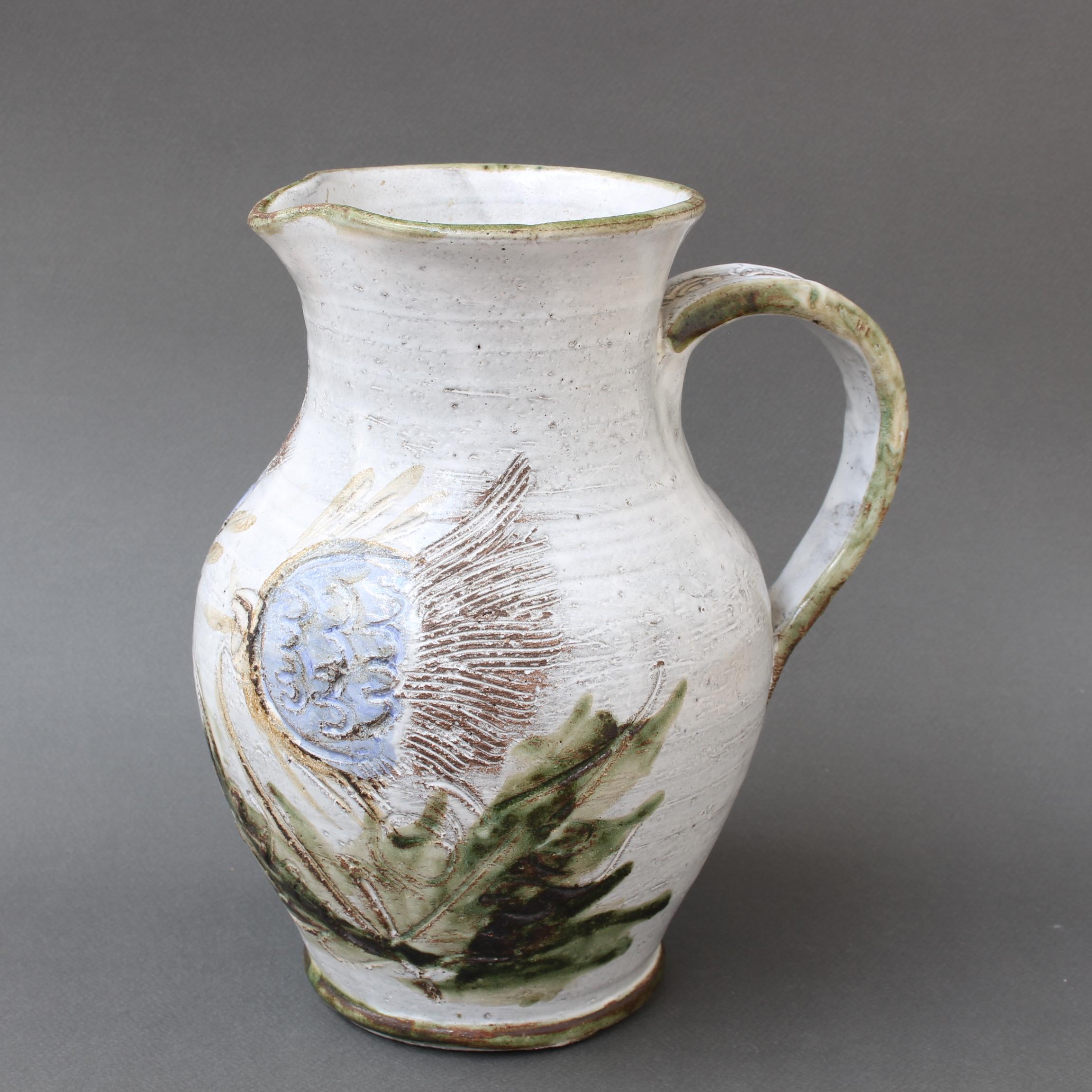 Large mid-century ceramic pitcher (circa 1970s) by Albert Thiry. A classic Thiry design and decoration scheme, this pitcher's base colour is done in a milky-white glaze with painted blue thistle flowers along with their green leaves. It is elegant