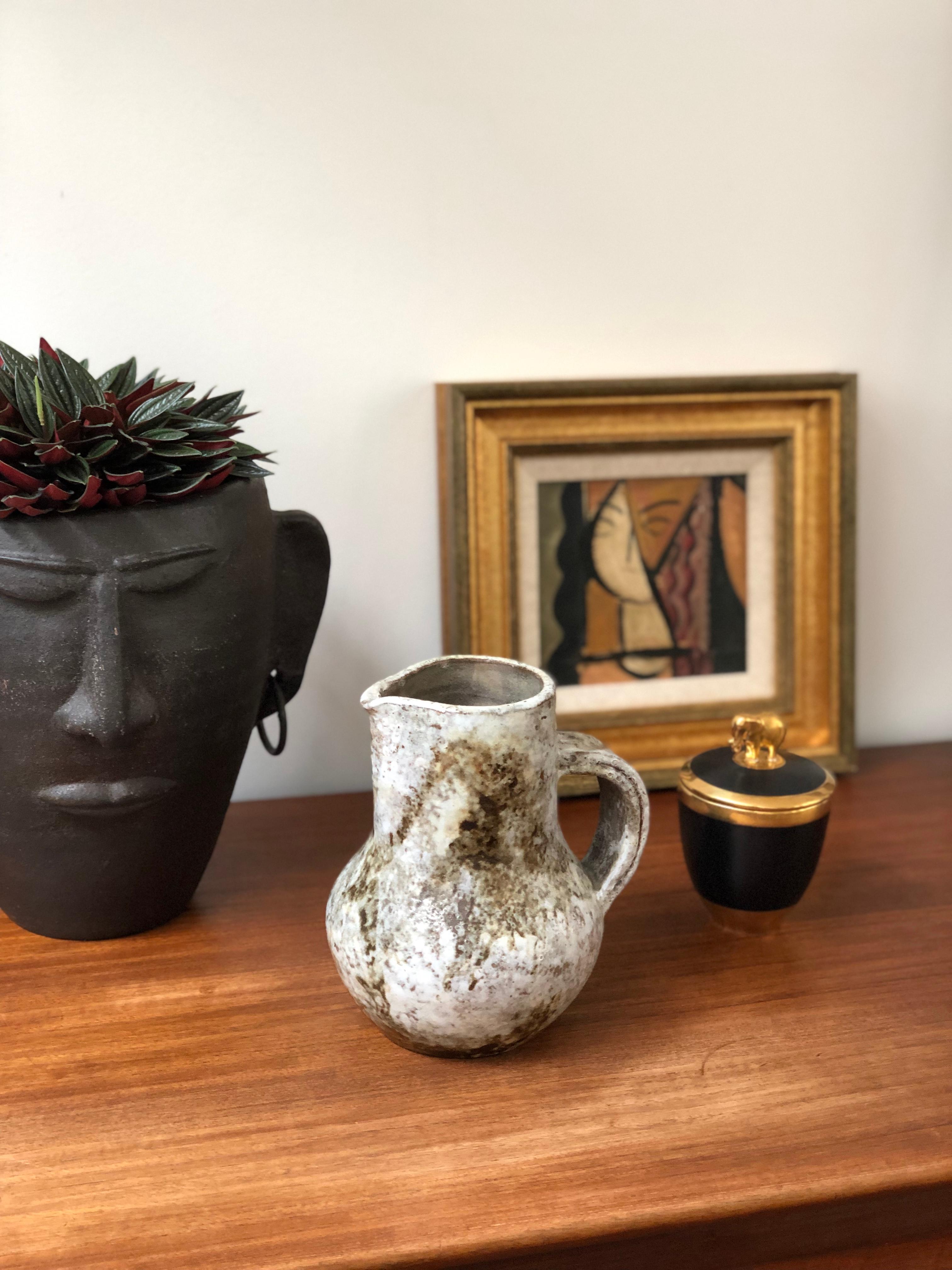 Midcentury ceramic pitcher / vase by Alexandre Kostanda (circa 1960s). This beautiful vessel presents a misty appearance with earth tones in brown and beige over a hazy, delicate white glazed base. In addition to being visually stunning, the piece