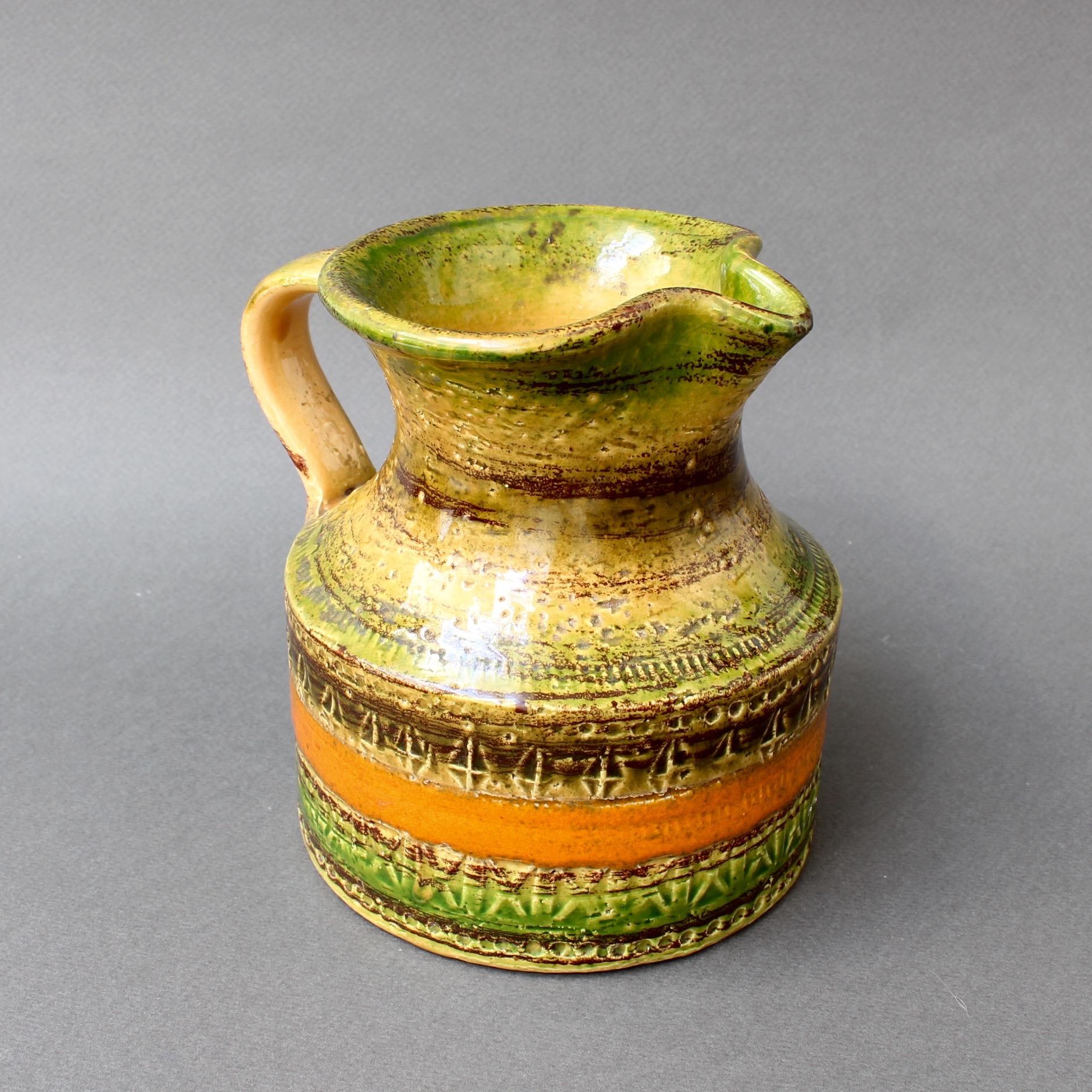 Midcentury decorative ceramic pitcher or carafe by Bitossi in avocado green with orange accents, (circa 1960s). A stout and sturdy design with loads of charm and character. A very attractive sheen has been applied to the variegated surface which