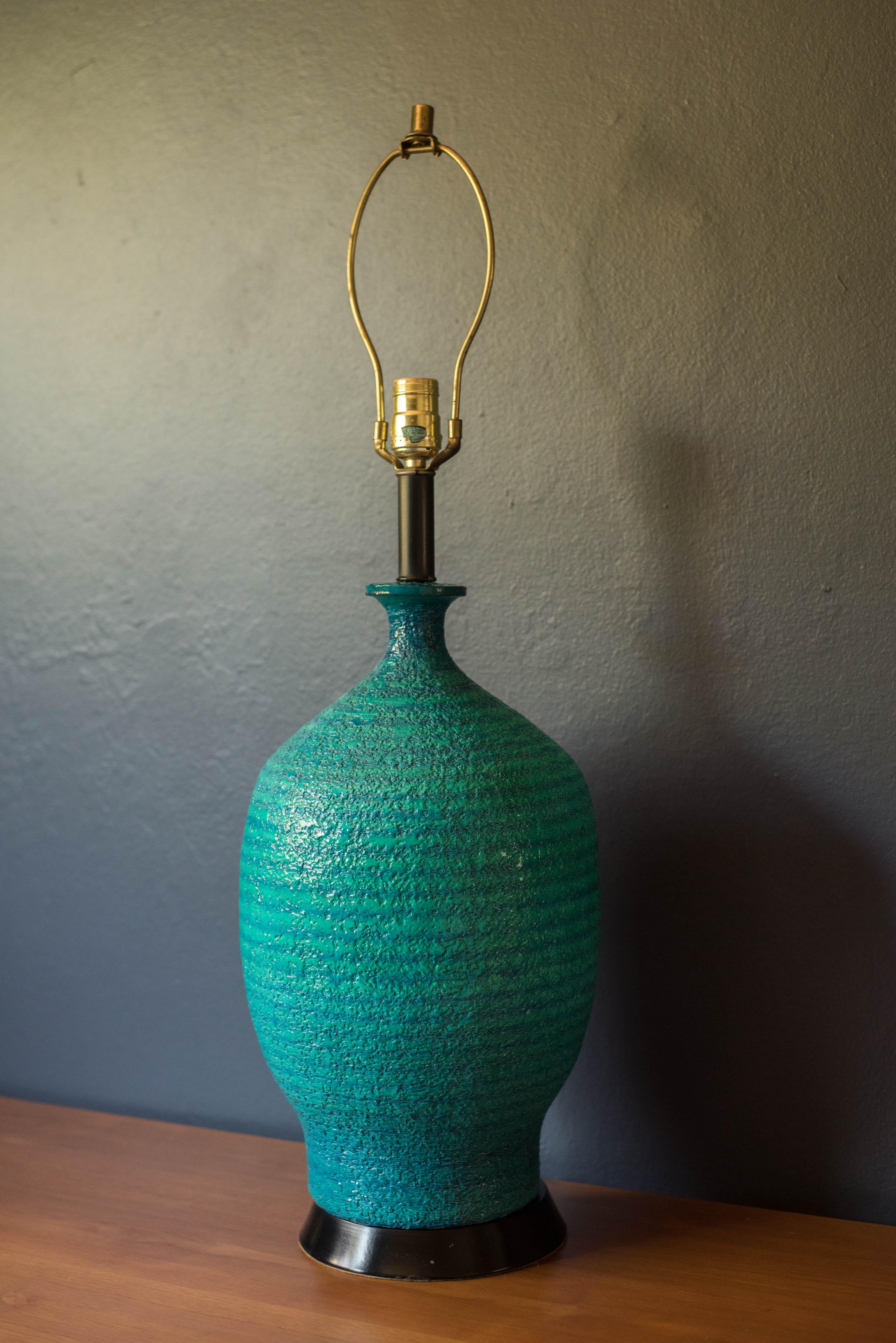 Vintage ceramic pottery table lamp circa 1960's. This piece features a vibrant mixture of blue and green with a textured glaze finish. Functions with a three way switch to emit a soft or brighter glow. Shade is not included.
