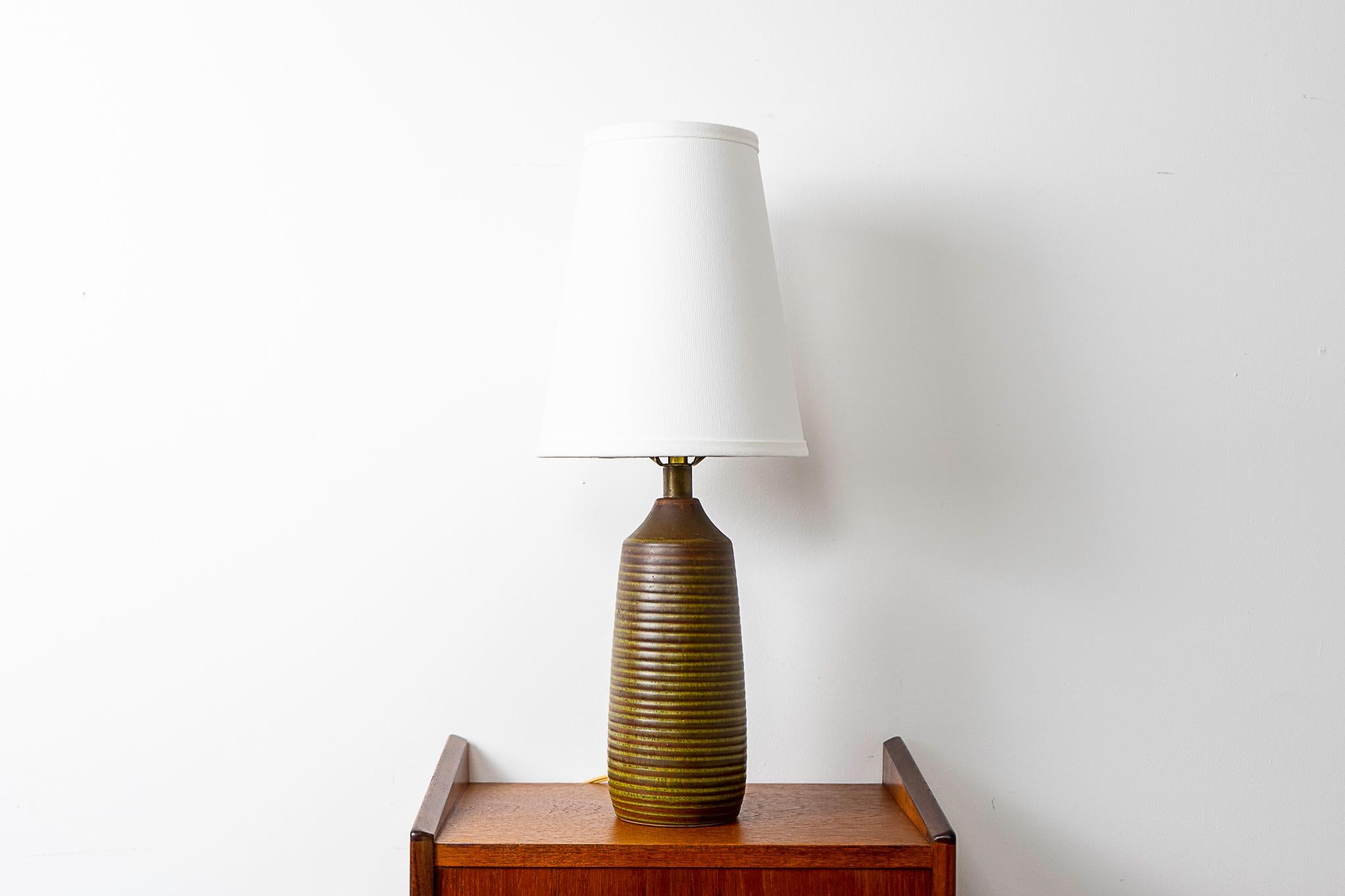 Ceramic table lamp by Lotte & Gunnar Bostlund, circa 1960's. The lovely earth tone glaze with dramatic rings pairs perfectly with the custom canvas textured shade. Excess cord slack can be neatly tucked away inside the lamp base. Use a trilight bulb