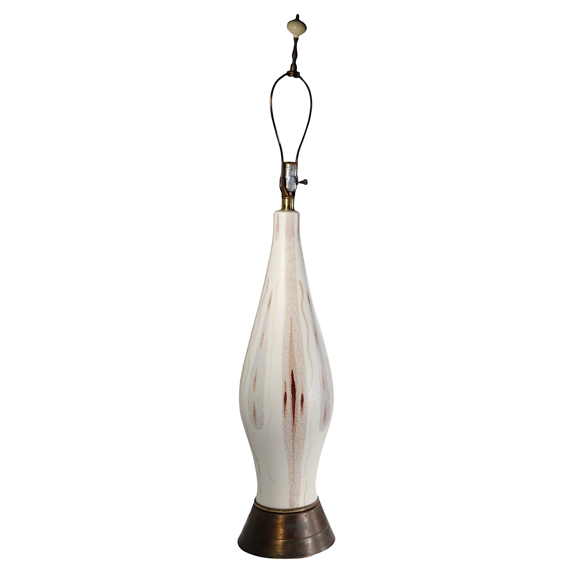 Lámpara de sobremesa de cerámica de mediados de siglo, con un cuerpo blanco hueso y un motivo decorativo abstracto en tonos tierra, marrón y gris, sobre una base de madera.  zócalo metálico. La lámpara está en muy buenas condiciones, limpia,