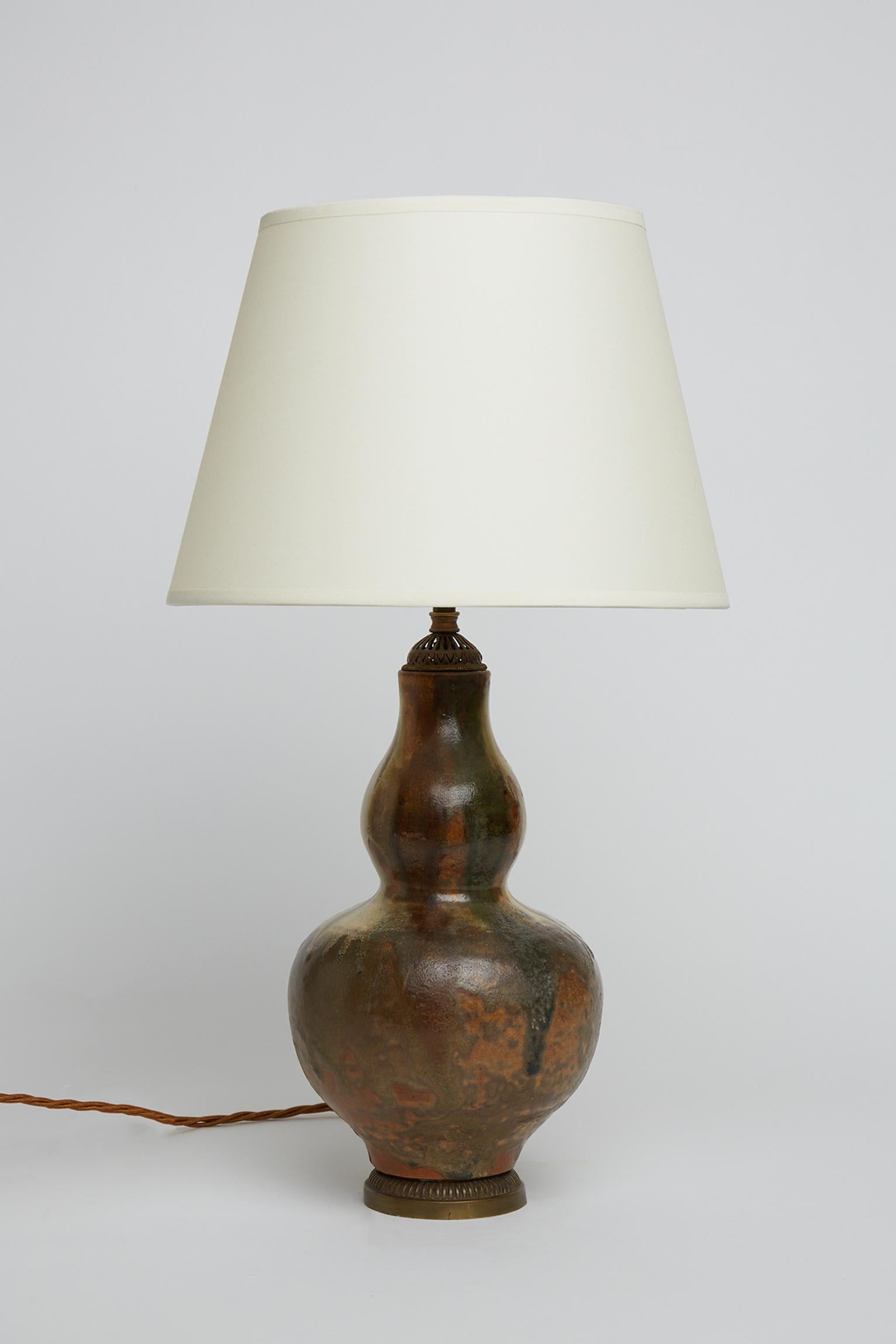 A mid-century table lamp, made of a stoneware double gourd shape ceramic vase with a polychrome glaze, mounted with 19th Century brass mounts.
France, Circa 1950.
Measures: with the shade: 58 cm high by 35 cm diameter.
Lamp base only: 41 cm high