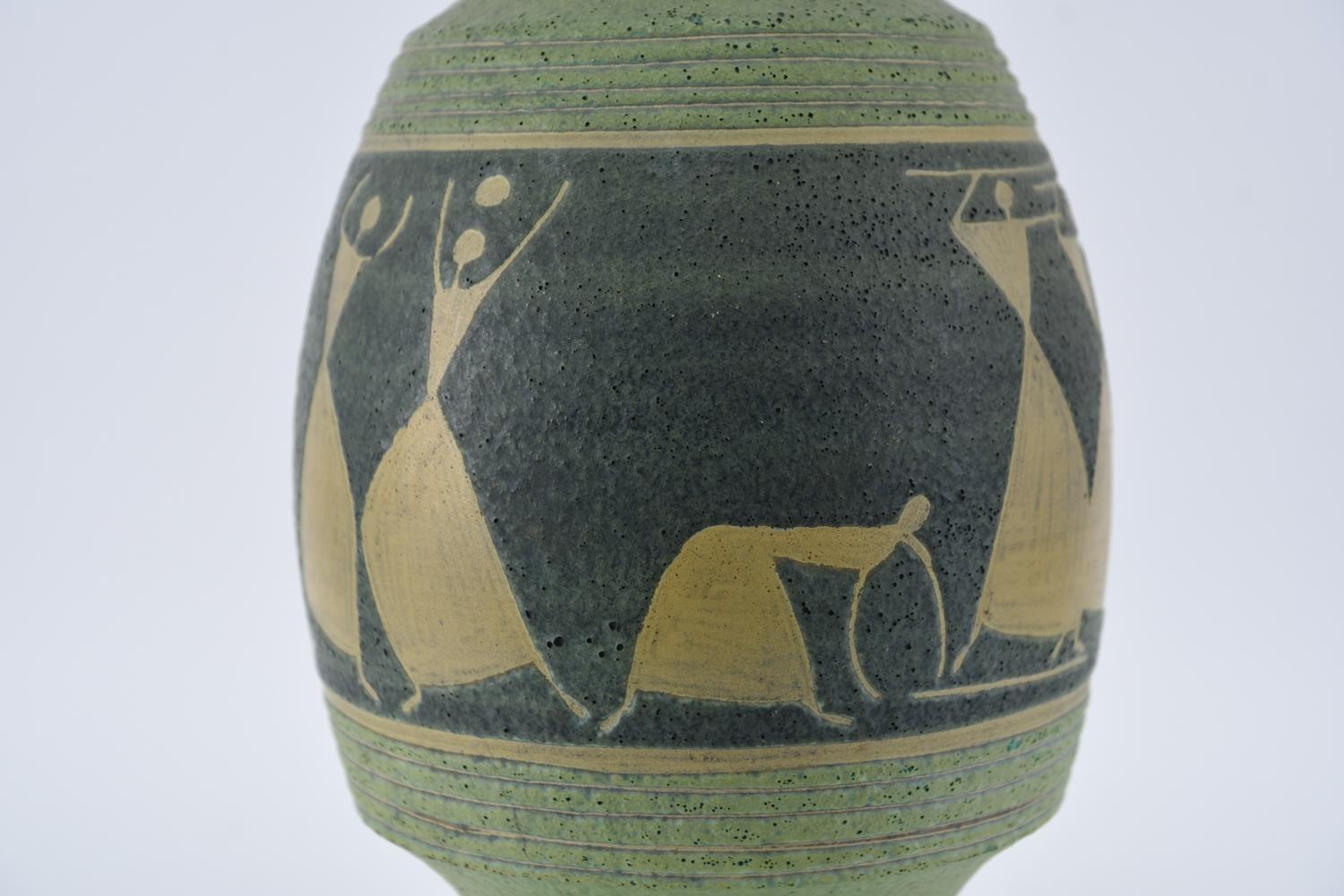 Decorated in the Primitive style, with impressed schematic figures carrying sticks, balls, and umbrellas. Combed geometric lines, thick matte glaze with pinhole texture (possibly lava glaze). Likely earthenware or a darker-colored stoneware.