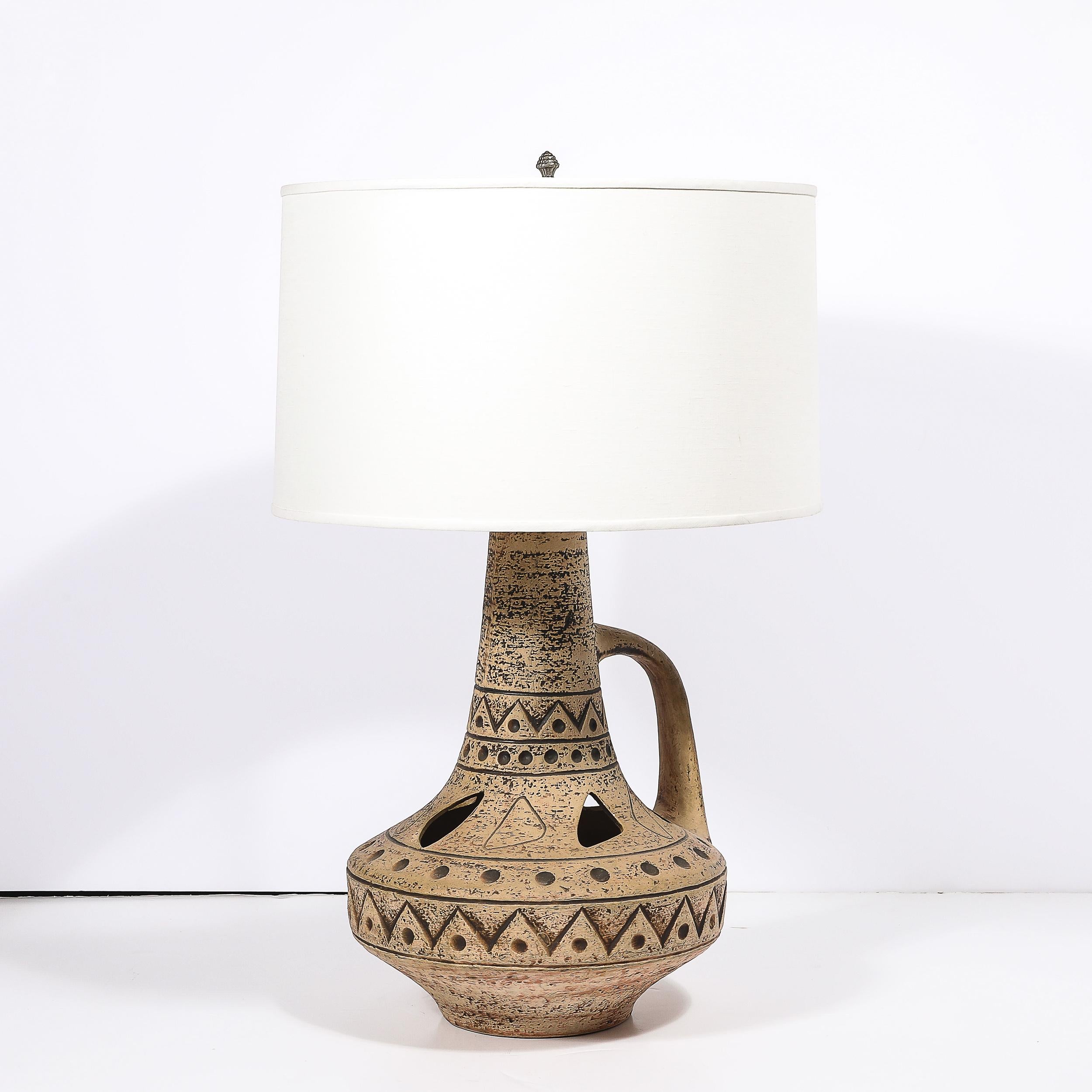 Cette lampe de table en céramique de style moderniste du milieu du siècle, fabriquée en France vers 1950, est un exemple exceptionnel de l'engagement de l'époque à combiner expression artistique et fonctionnalité. La base en céramique de la lampe