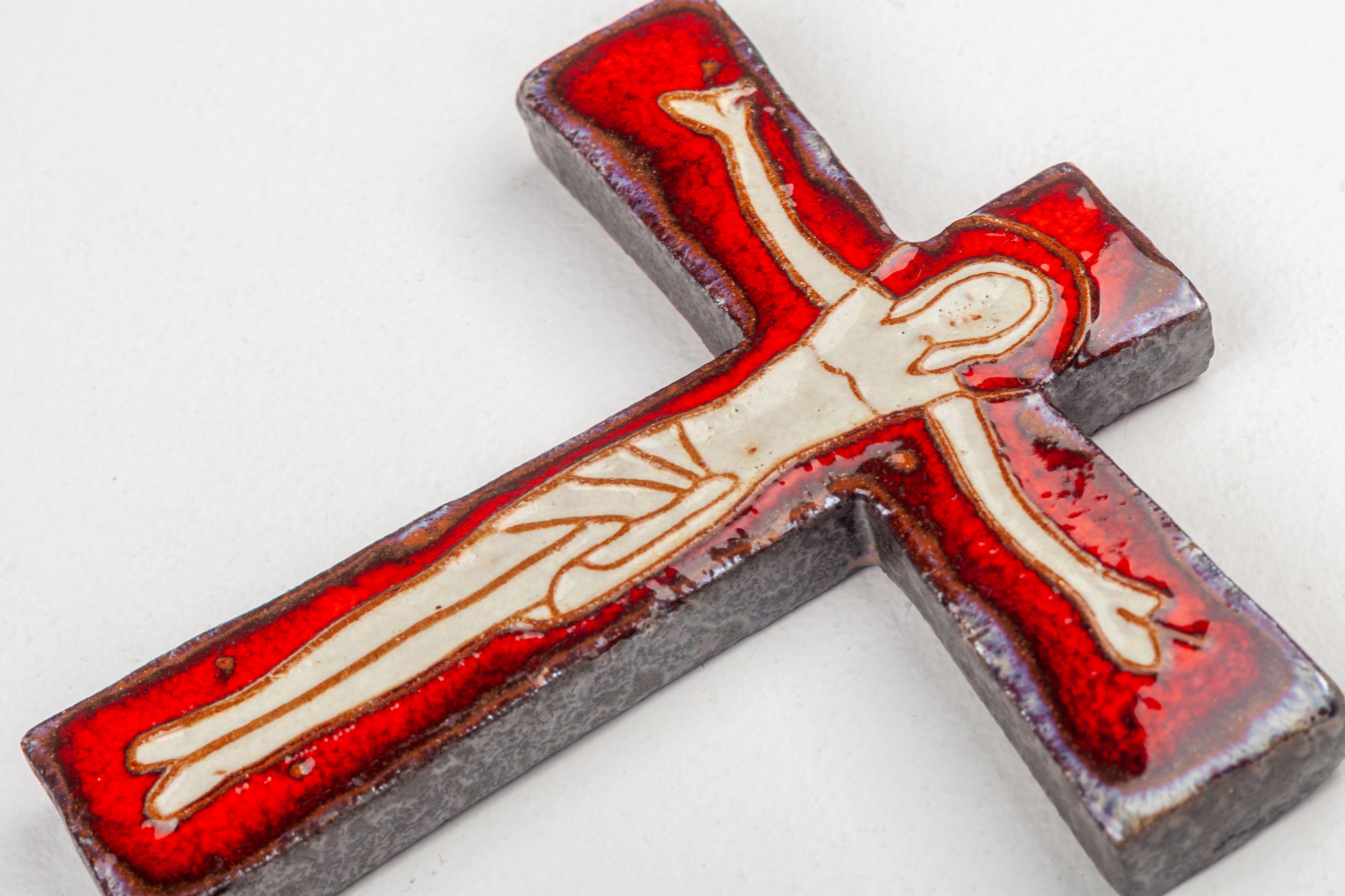 This wall cross is compact in wingspan and proportions, possessing a substantial thickness. The Christ figure on the cross radiates a glowy glossy red hue across most of the cross's surface, while the sides of the cross exhibit a glossy granite-like
