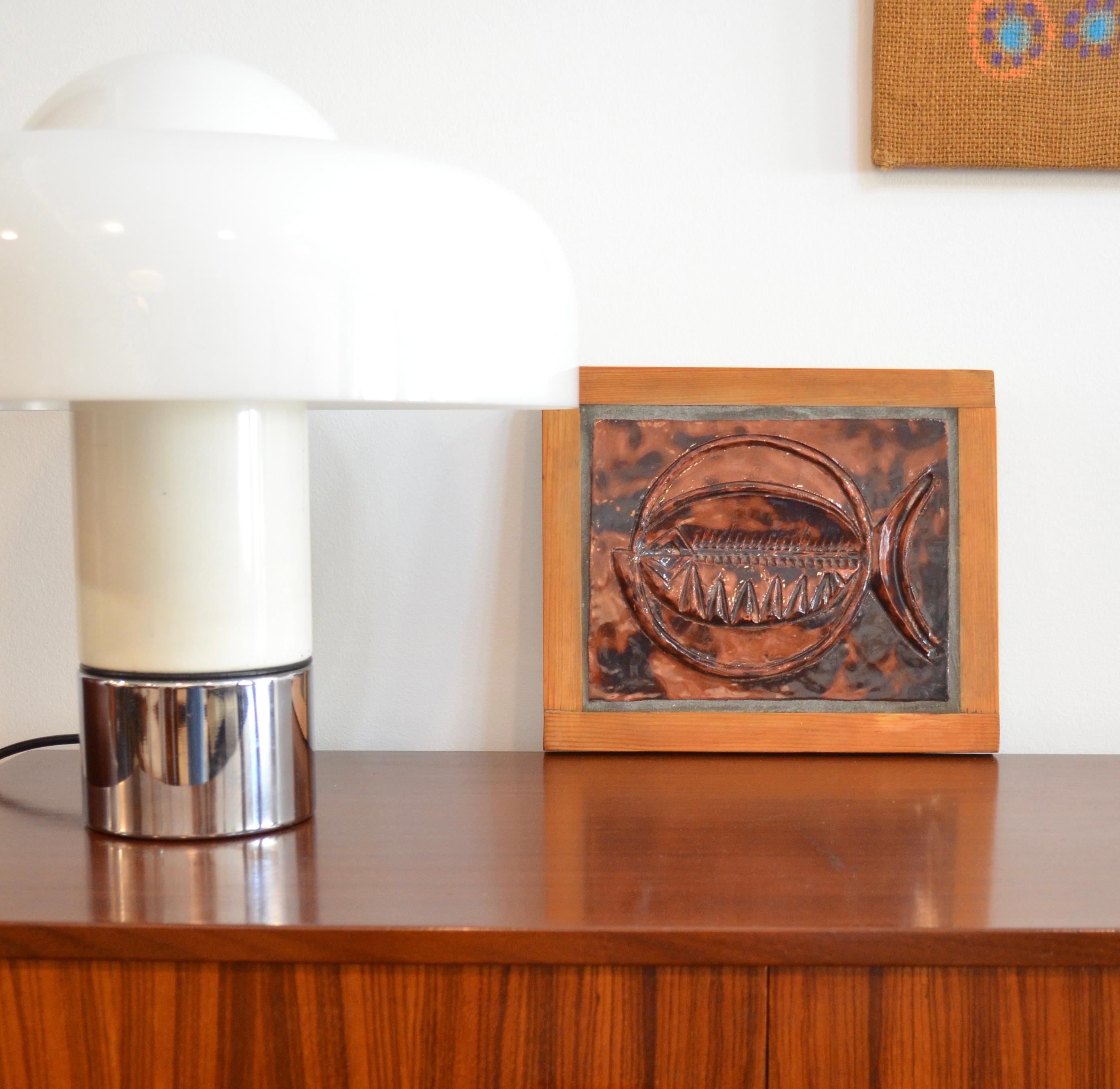 Sculpture murale en céramique représentant un poisson stylisé, montée sur une plaque en bois. La surface émaillée présente de riches nuances de brun et de noir, créant un magnifique contraste entre la brillance et la profondeur.
Cette pièce unique