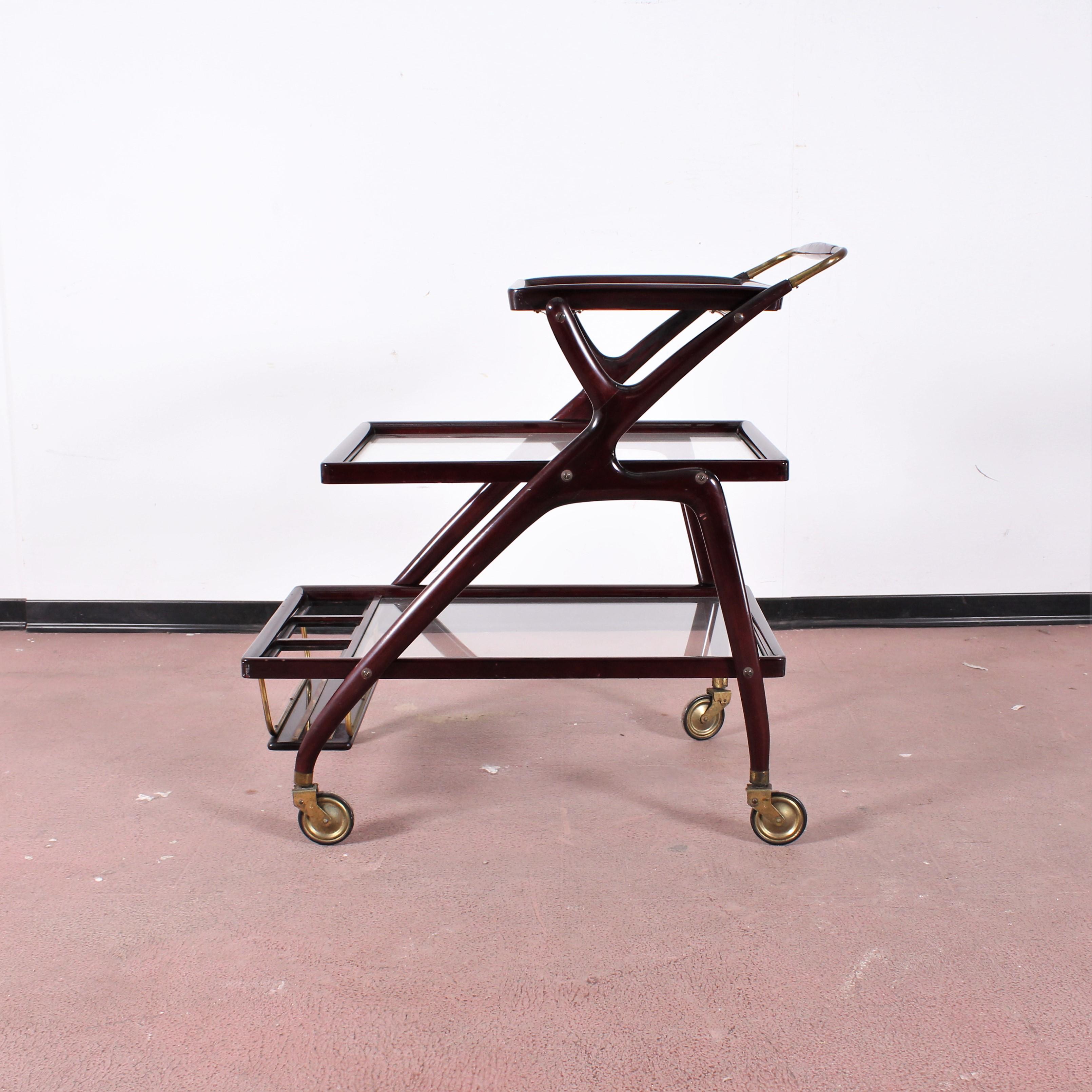 Geometric shapes in curved wood in this beautiful bar trolley attributed to Cesare Lacca. Three glass shelves with a small removable tray at the top, brass wheels.
Sturdy structure without damage.