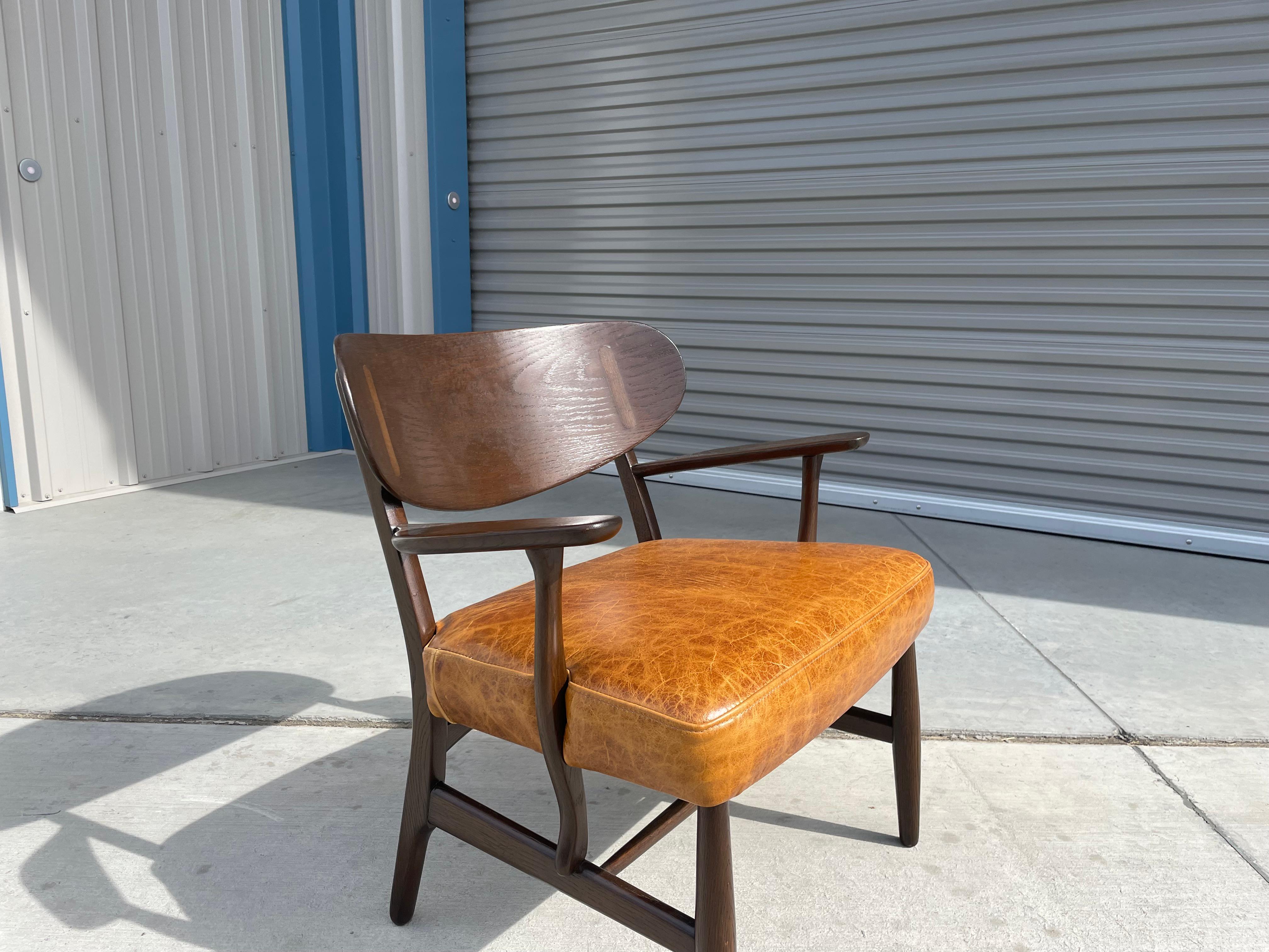 Midcentury CH-22 lounge chair designed by Hans Wegner and manufactured by Carl Hansen and Son in Denmark circa 1950s. This fantastic lounge chair features a dark oak frame and is newly reupholstered in brown leather fabric. This chair provides