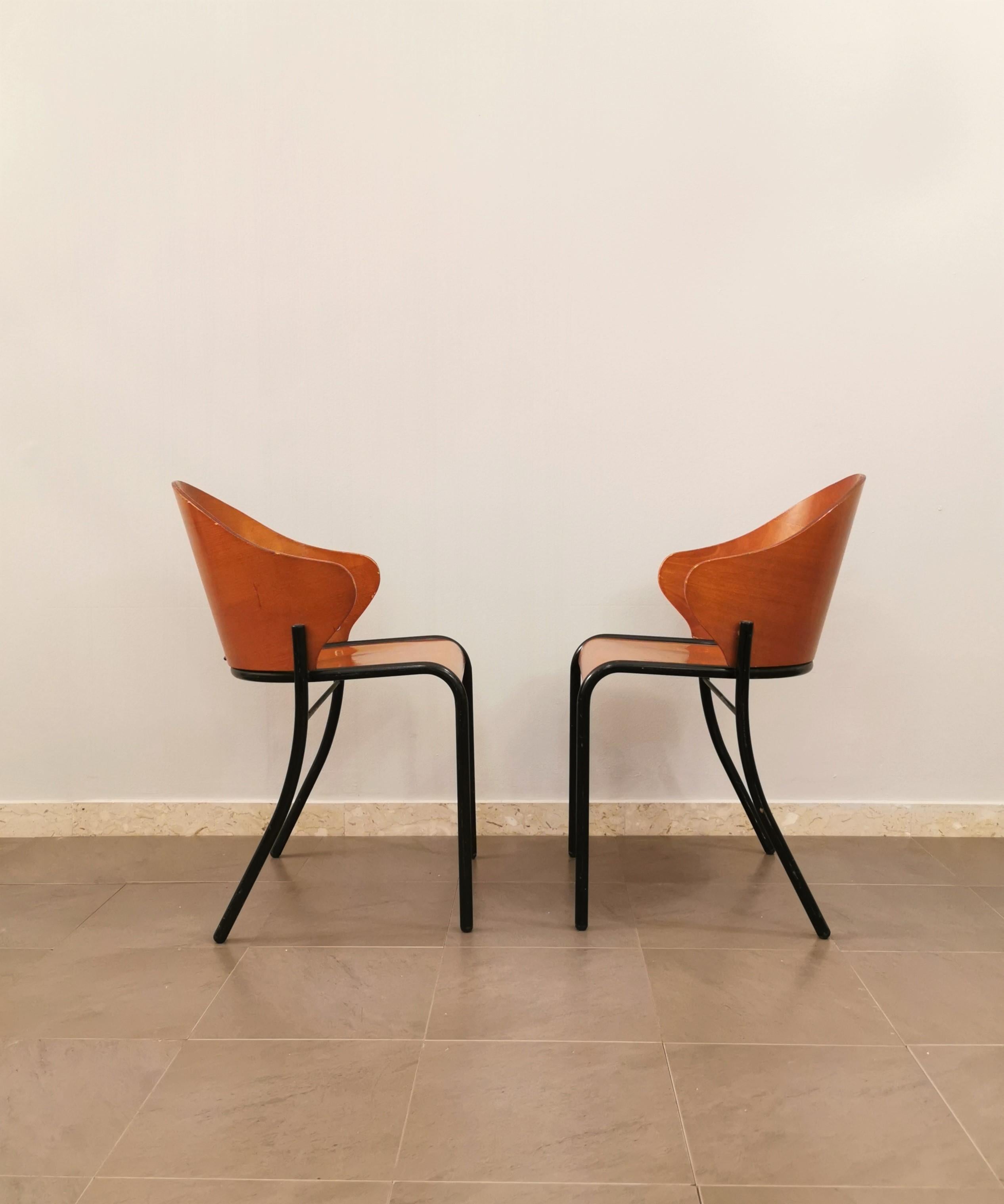 Set of 2 dining chairs in the style of Philippe Starck with unusual shapes produced in Italy in the 1960s. The chairs have a black enamelled tubular metal frame and back legs of a particular curved shape with seat and back in curved wood.
    